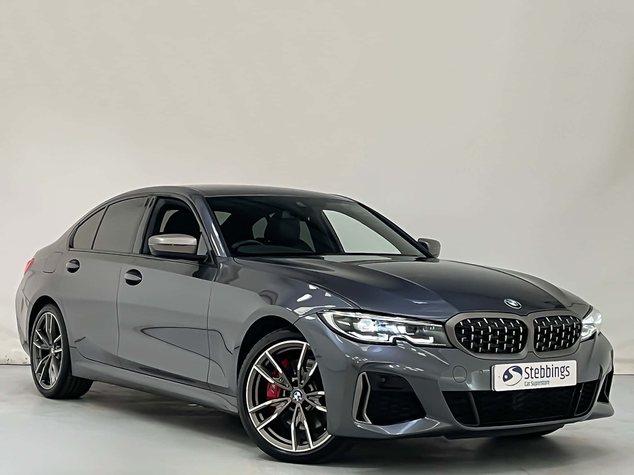 Bmw 3 Series 桌布 壁紙 — 一輛時尚的灰色BMW轎車，配備紅色制動卡鉗和合金輪圈，在極簡主義的攝影棚環境中展示。
