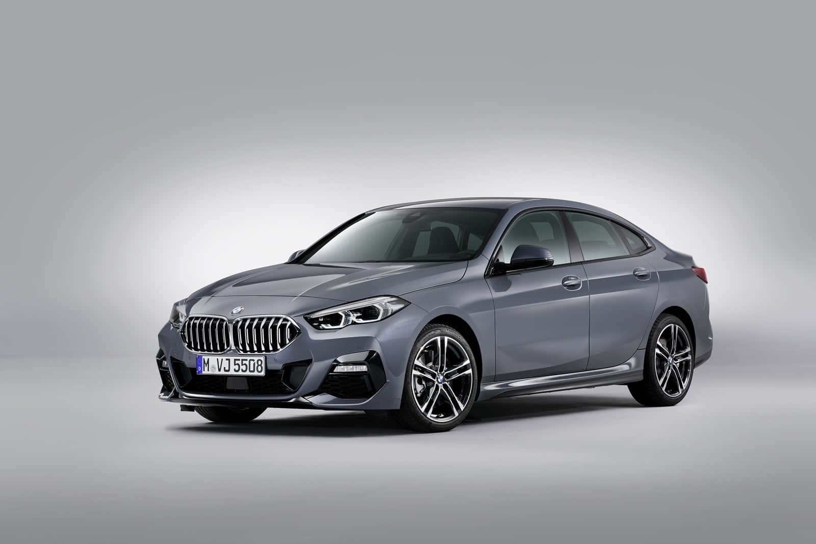 Bmw 2 Series 桌布 壁紙 — 一輛時尚的灰色BMW轎車，配備運動型合金輪圈，在簡約的攝影棚背景下展示。