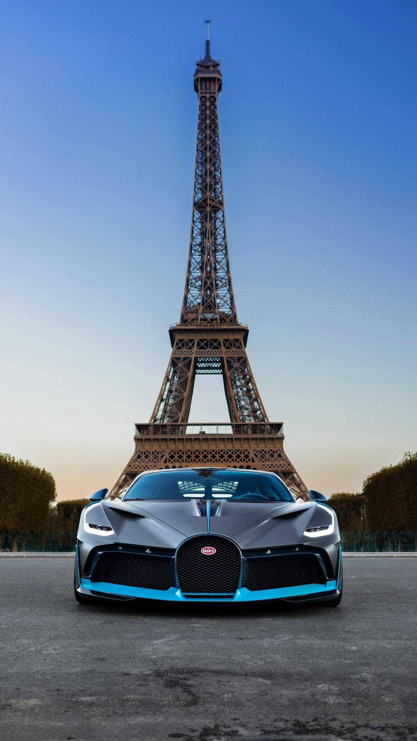 Cool Bugatti 桌布 壁紙 — 一輛時尚的灰色Bugatti超跑，帶有藍色點綴，在日落時停泊在艾菲爾鐵塔前。