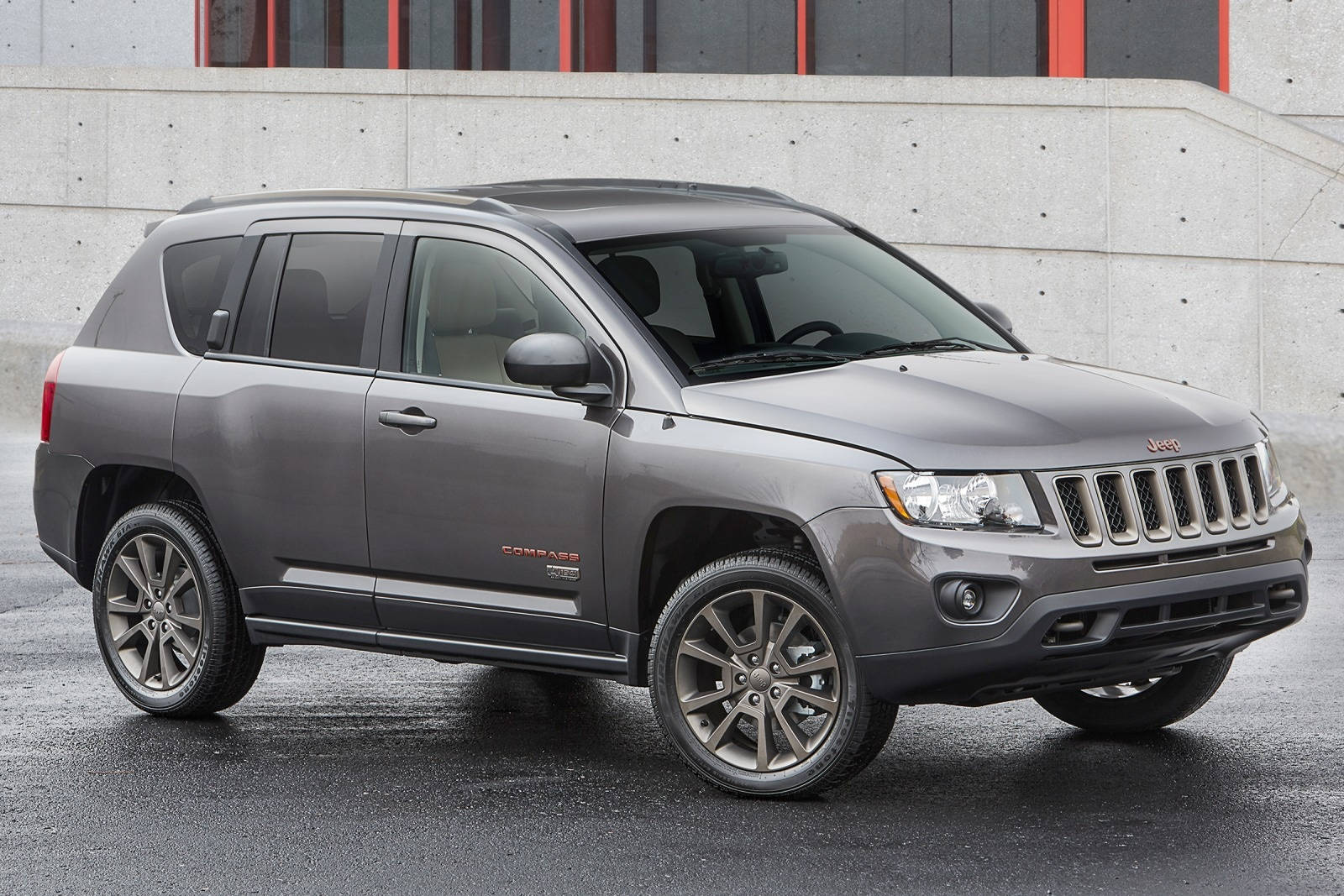 黑色美學 桌布 壁紙 — 一輛時尚的灰色Jeep Compass SUV停放在濕漉漉的路面上，背景是帶有紅色點綴的現代混凝土牆。