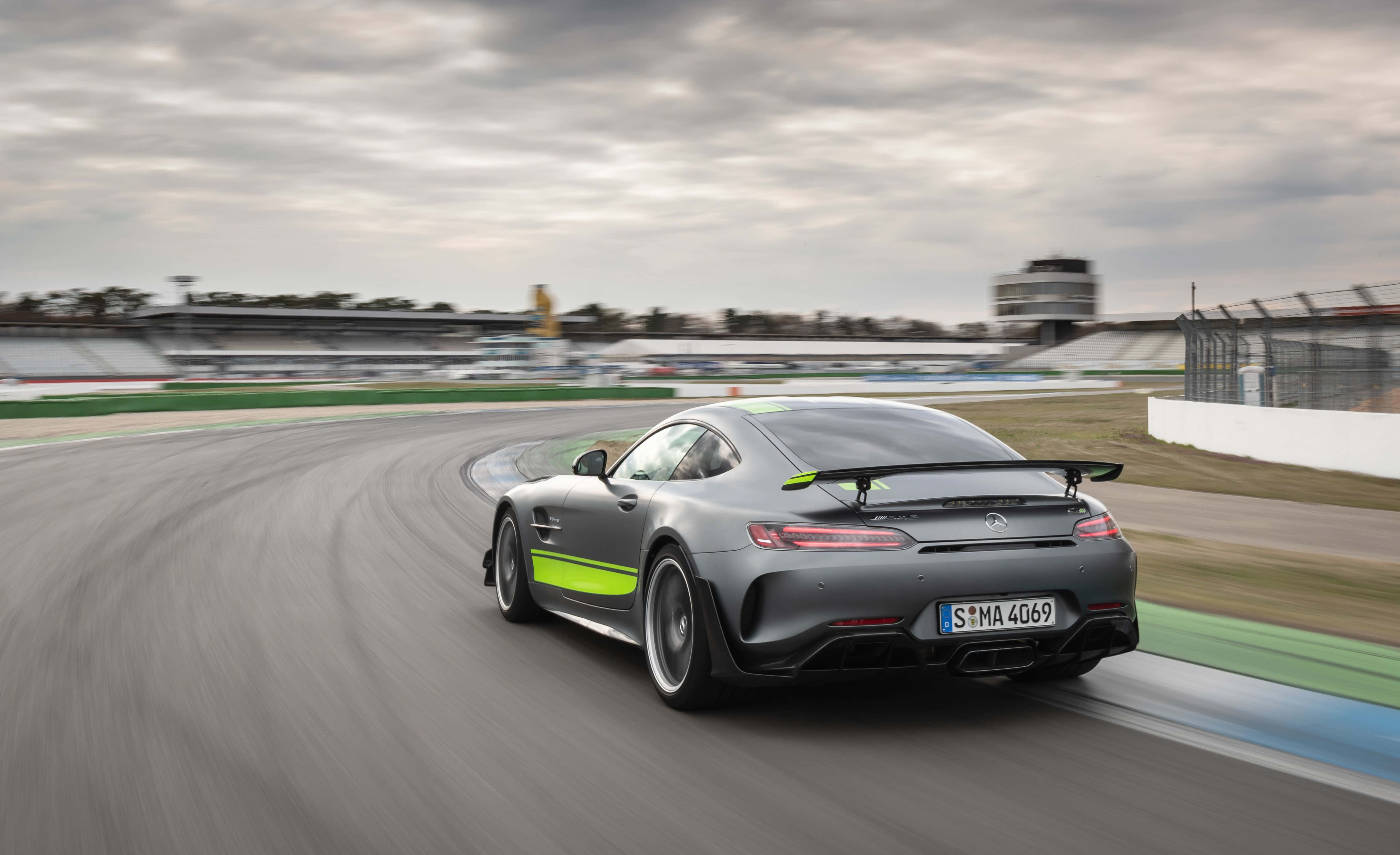 race car 桌布 壁紙 — 一輛時尚的灰色Mercedes-AMG GT R，帶有螢光綠色點綴，在陰天潮濕的賽道上奔馳。