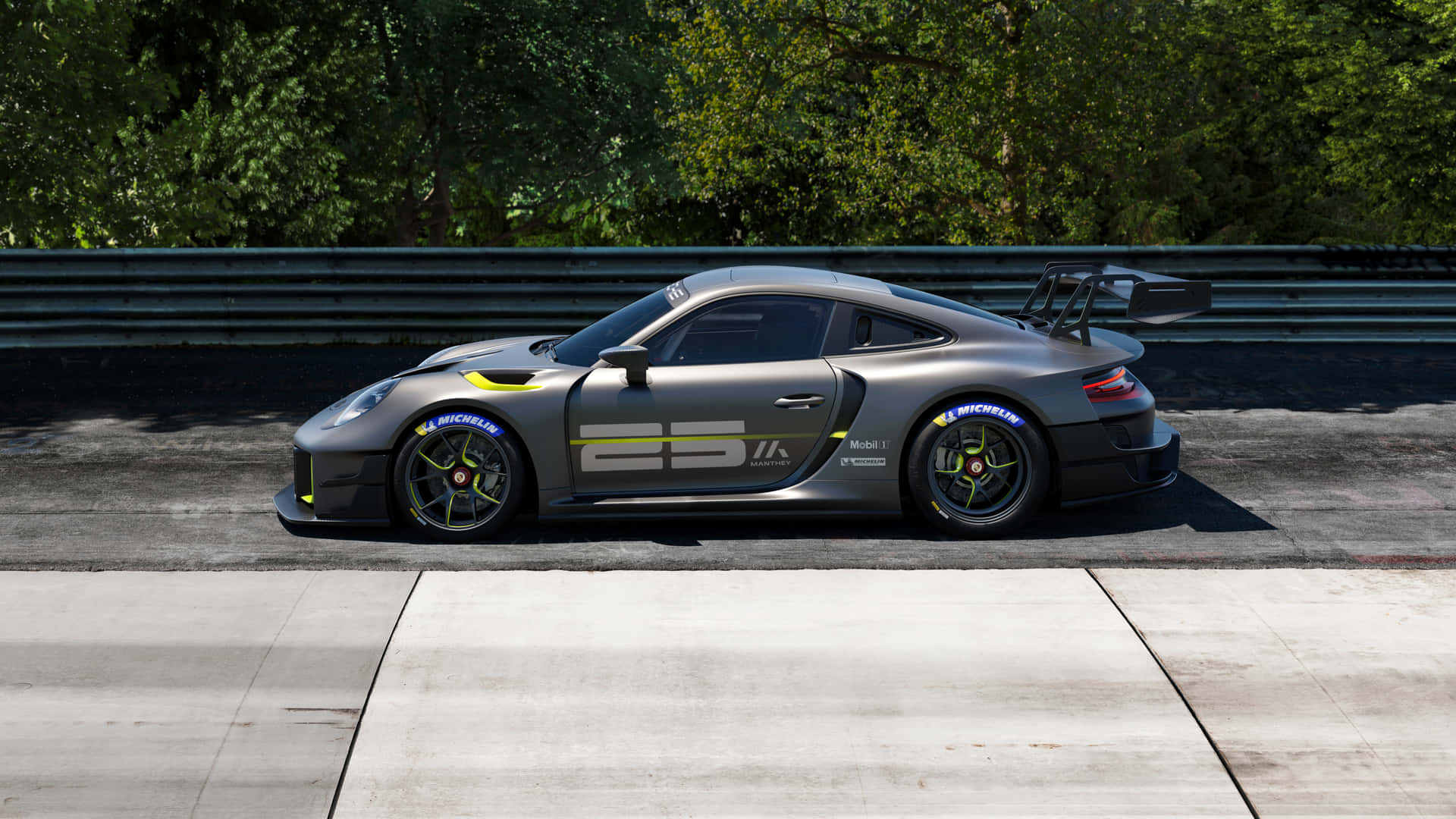 保時捷 桌布 壁紙 — 一輛時尚的灰色保時捷911 GT3 RS賽車帶有黃色點綴，在明亮的日光下停在混凝土賽道上，旁邊是綠色森林屏障。