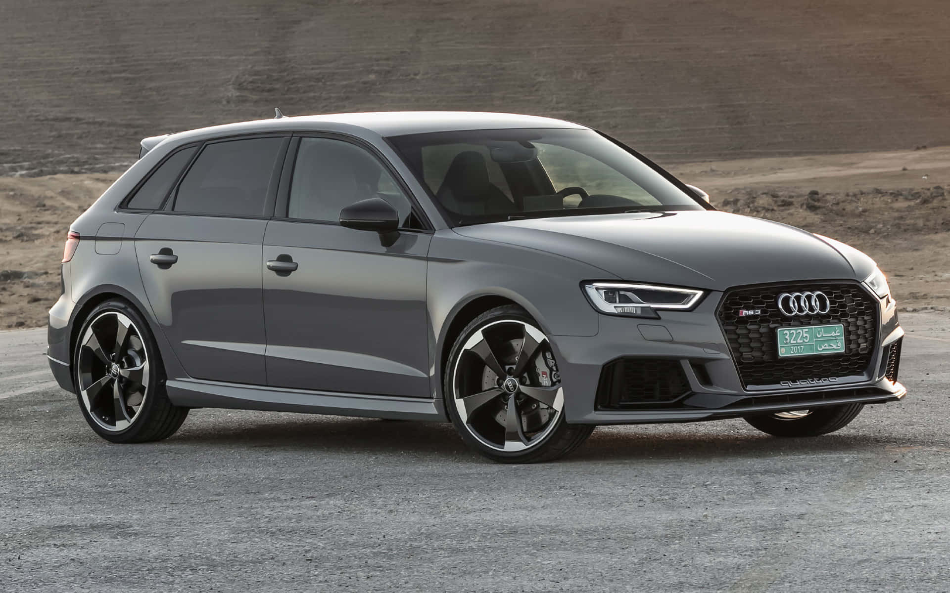 Rs 桌布 壁紙 — 一輛時尚的灰色奧迪RS3 Sportback停在碎石上，背景是沙漠山丘。