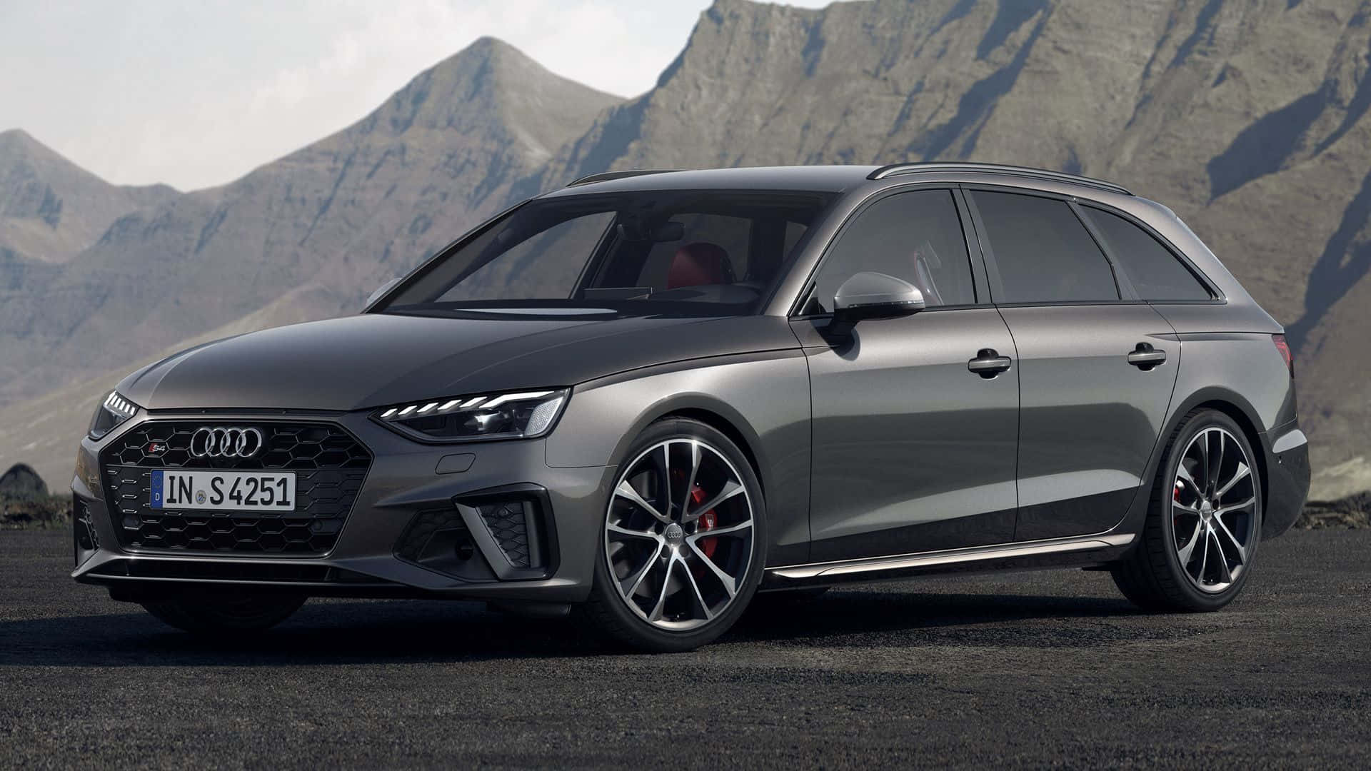 Audi S4 桌布 壁紙 — 一輛時尚的灰色奧迪S4旅行車停在柏油路上，背景是崎嶇的山脈，光線明亮。