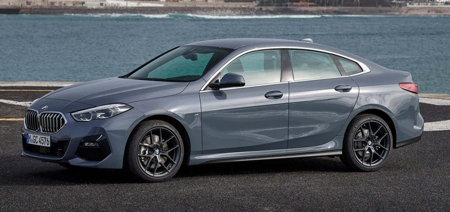 Bmw 2 Series 桌布 壁紙 — 一輛時尚的灰色寶馬轎車停放在沿海公路上，背後有海浪拍打。