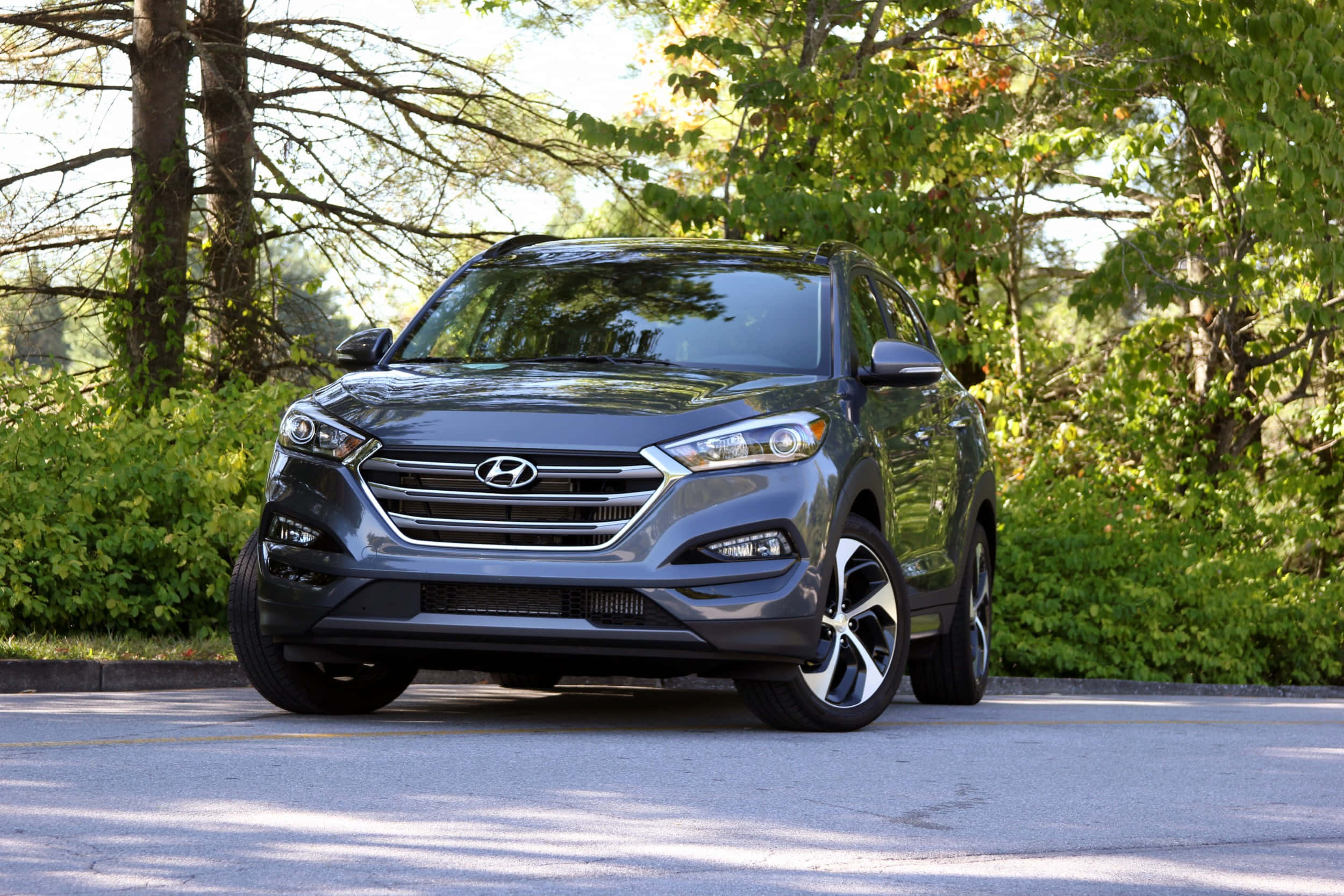 Hyundai 桌布 壁紙 — 一輛時尚的灰色現代Tucson SUV停在瀝青路上，斑駁的陽光透過秋樹篩落。