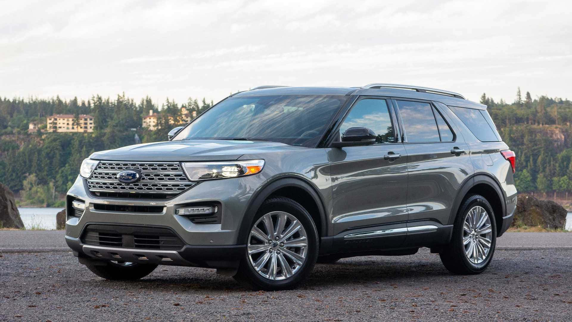 Ford Explorer 桌布 壁紙 — 一輛時尚的灰色福特Explorer SUV停泊在碎石路上，旁邊是森林湖泊，遠處有房屋，天空多雲。