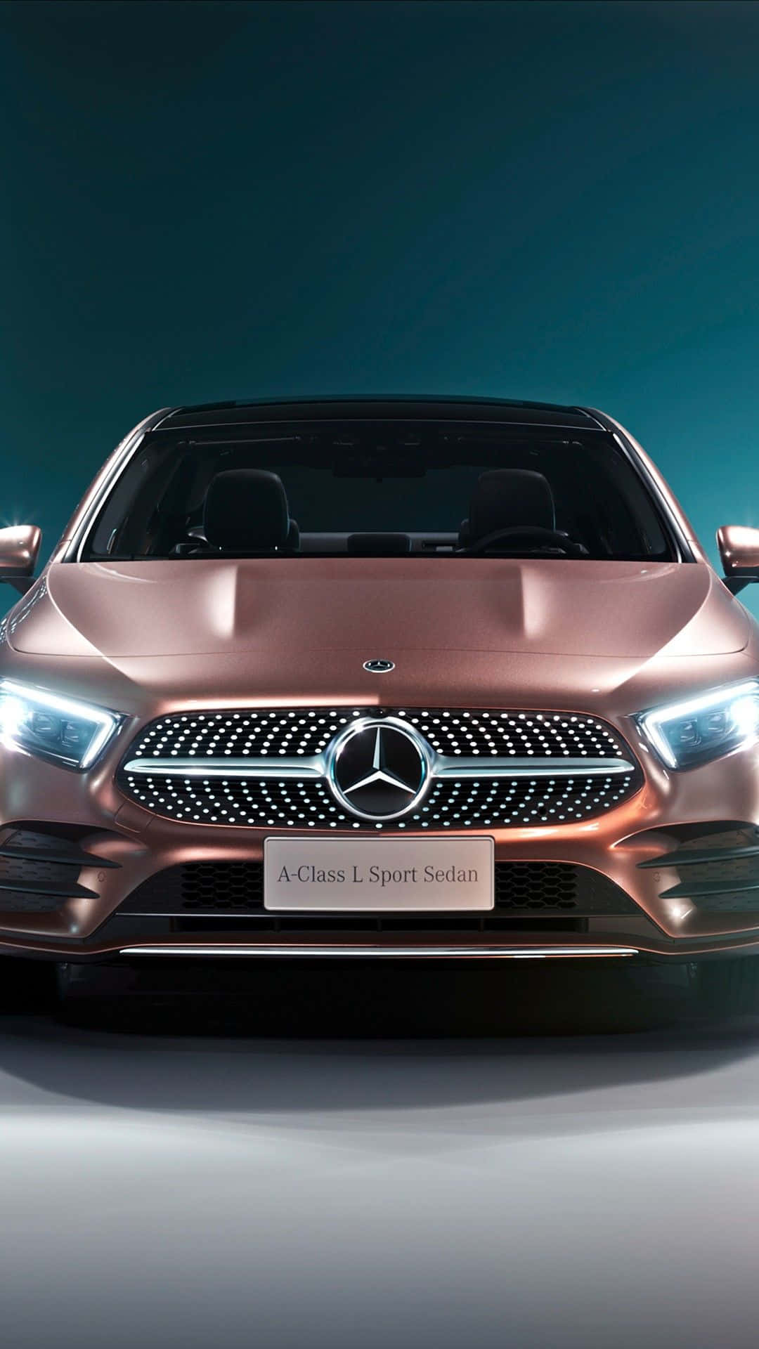 Mercedes 桌布 壁紙 — 一輛時尚的玫瑰金色賓士A-Class L Sport Sedan在攝影棚燈光下，在深藍綠色背景前閃閃發光。