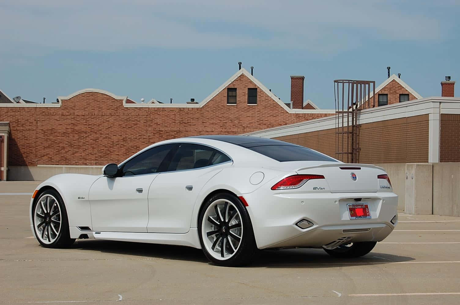 Fisker 桌布 壁紙 — 一輛時尚的白色 Jaguar F-Type 跑車停放在陽光明媚的停車場，背景是磚造建築。