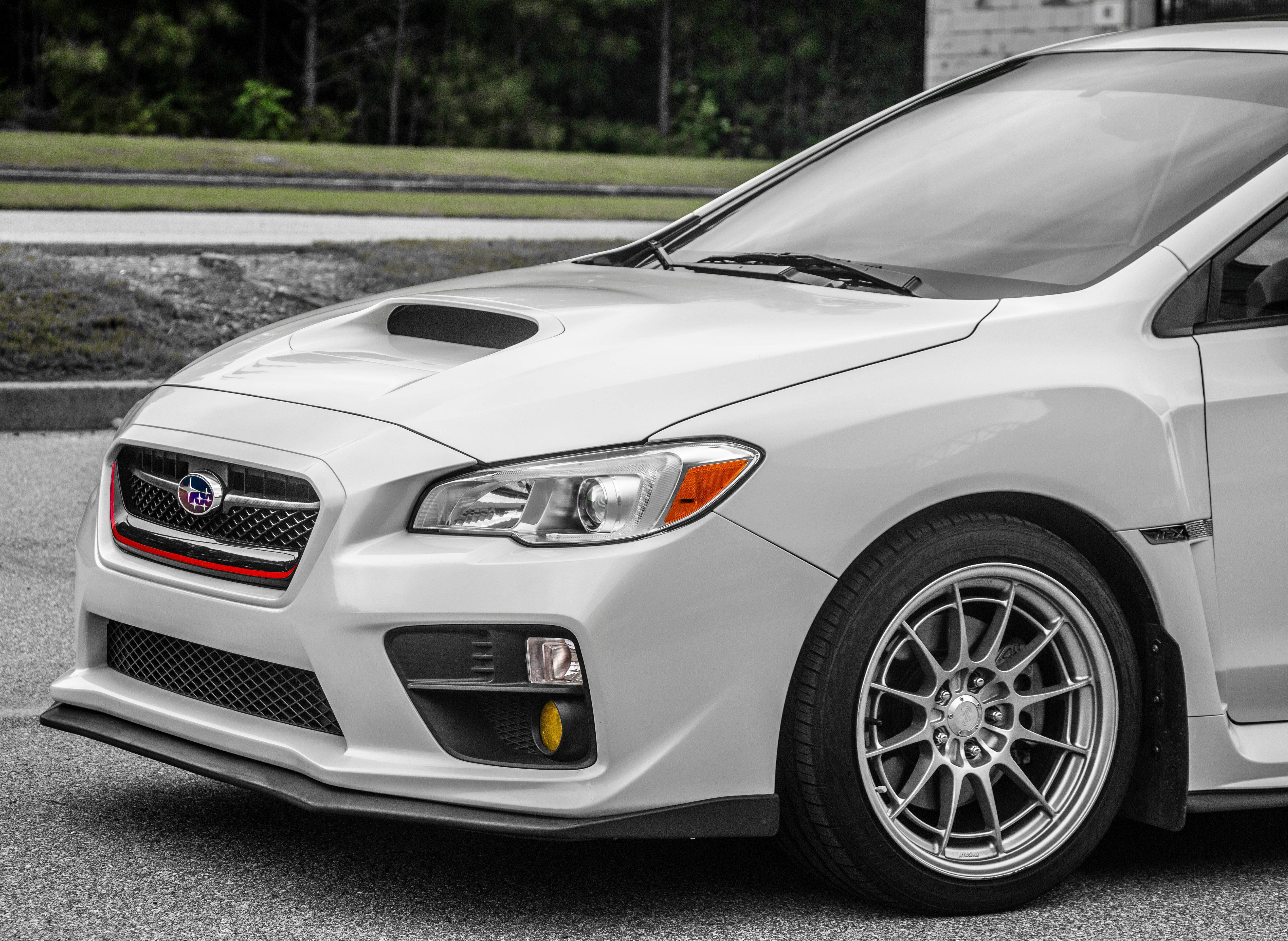 昴 桌布 壁紙 — 一輛時尚的白色 Subaru WRX STI 跑車，帶有紅色格柵裝飾和定制合金輪圈，停在瀝青路面上。