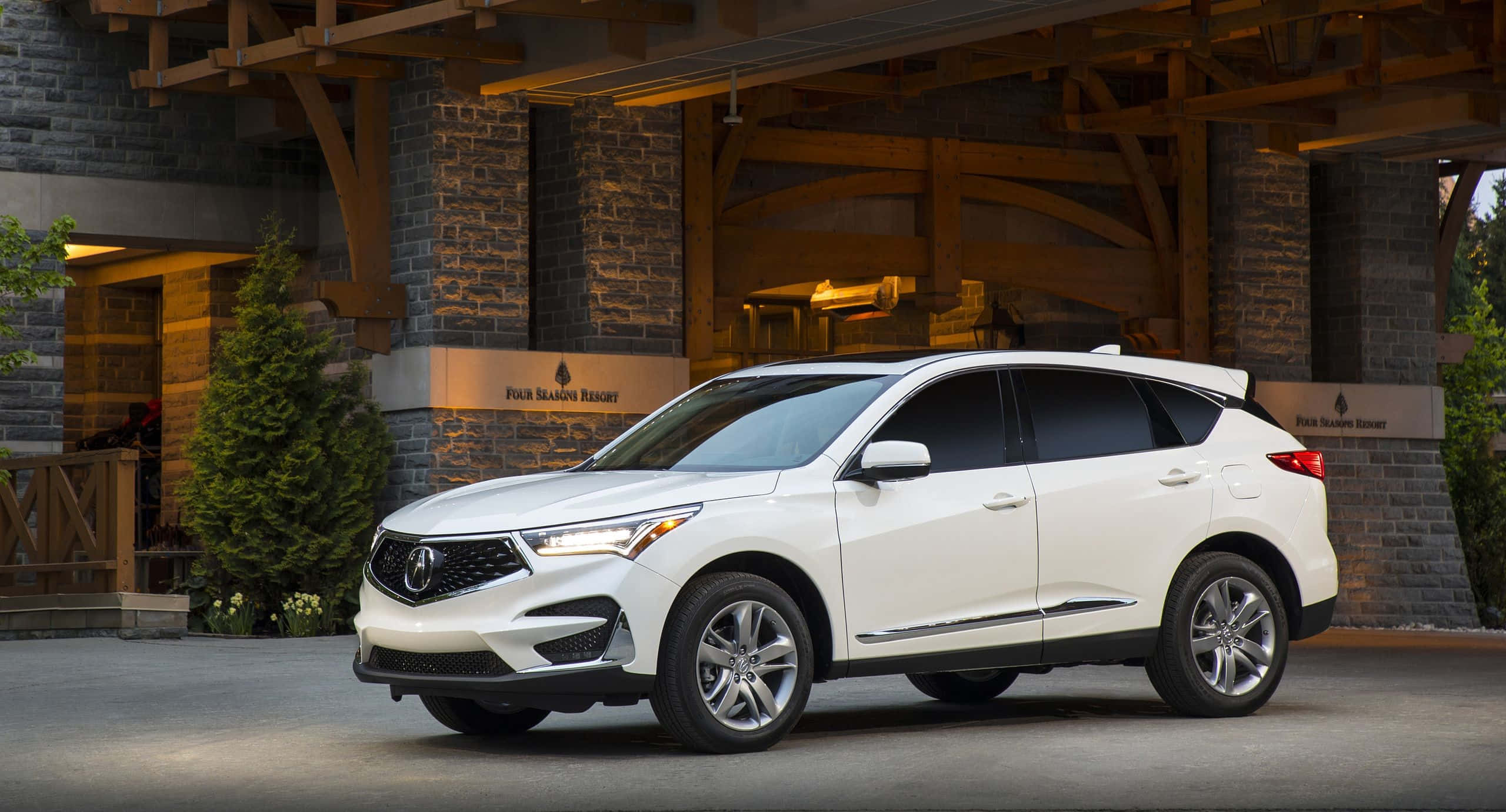 Acura Rdx 桌布 壁紙 — 一輛時尚的白色Acura SUV停在質樸的石木小屋前，室內燈光溫暖。