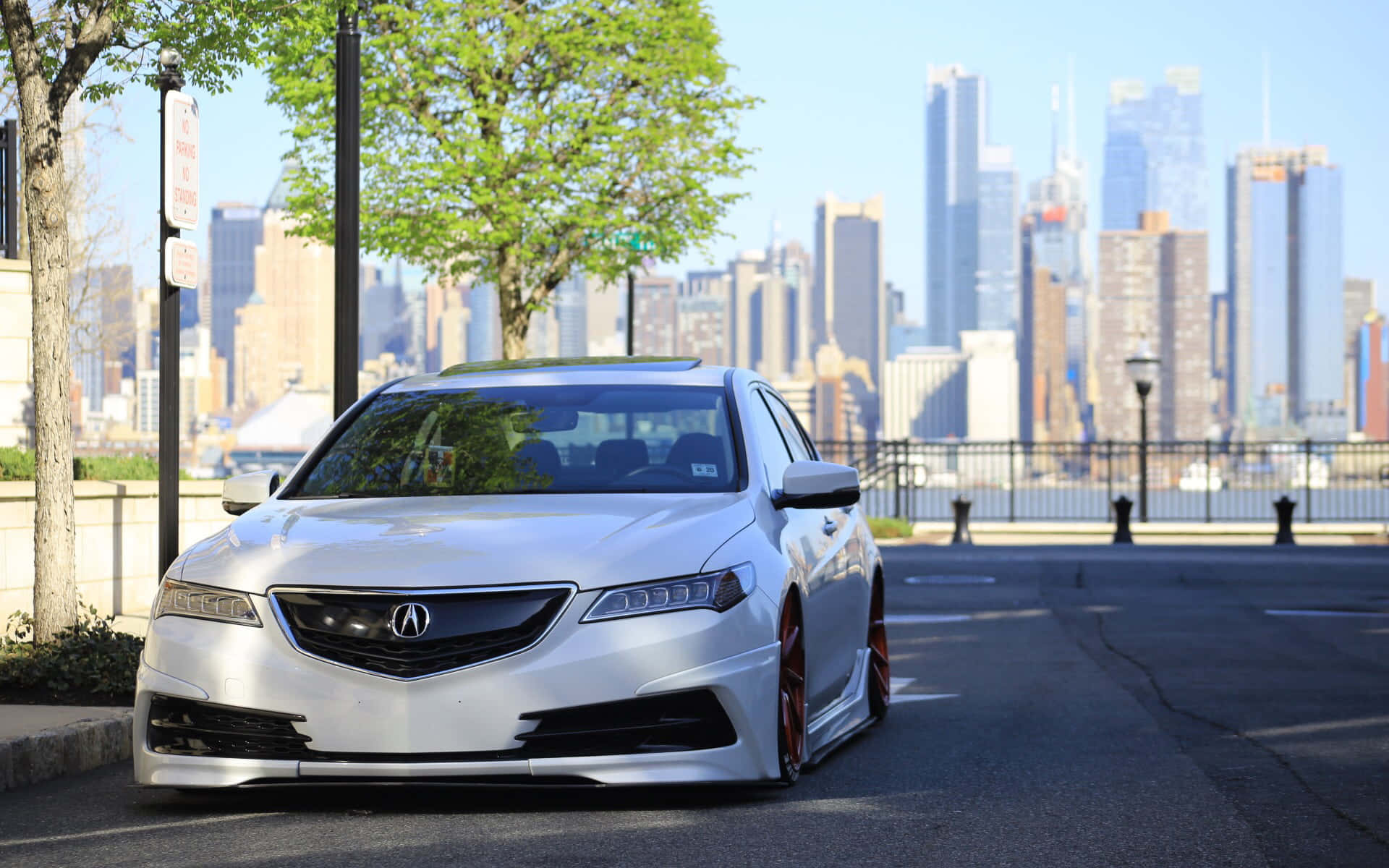 Acura Tlx 桌布 壁紙 — 一輛時尚的白色Acura轎車，帶有紅色制動卡鉗，停放在城市街道上，背景是模糊的摩天大樓天際線。