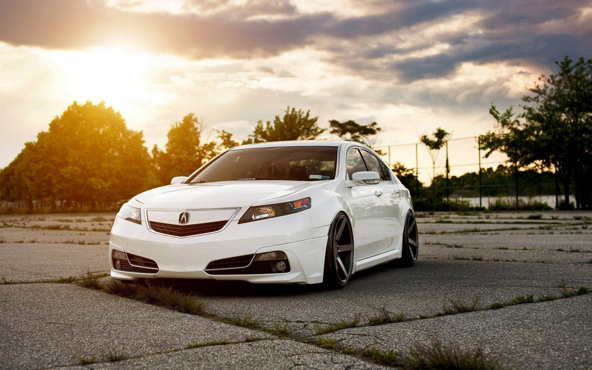 Acura 桌布 壁紙 — 一輛時尚的白色Acura轎車配備定制輪圈，低趴於裂開的瀝青路面上，金色夕陽光芒穿過戲劇性的雲層。