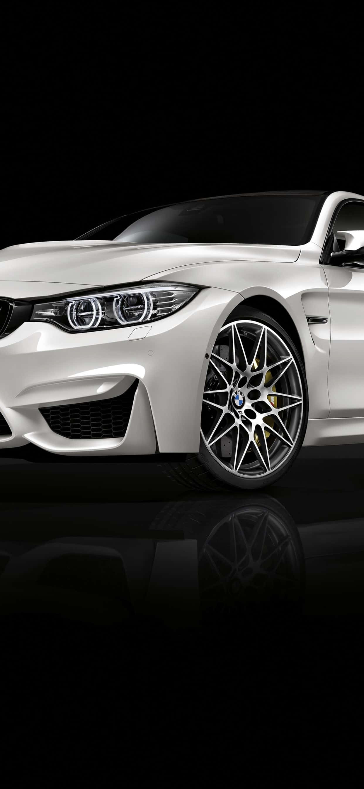 Bmw iPhone 桌布 壁紙 — 一輛時尚的白色BMW跑車，配備發光頭燈和金色煞車卡鉗，在黑色背景上展示，帶有光澤反射。