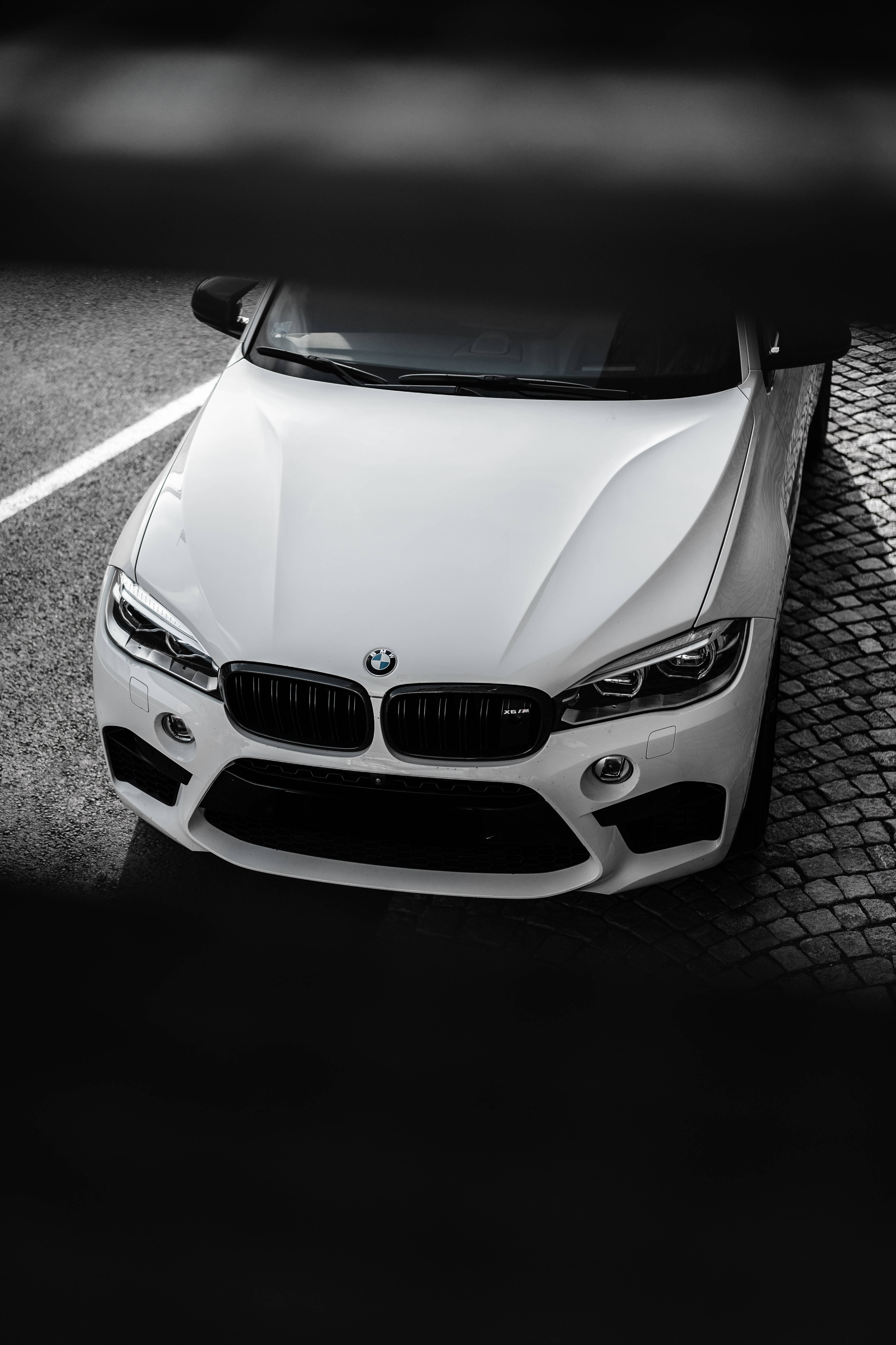 m 桌布 壁紙 — 一輛時尚的白色BMW跑車停泊在鵝卵石街道上，在戲劇性的高對比度燈光下。