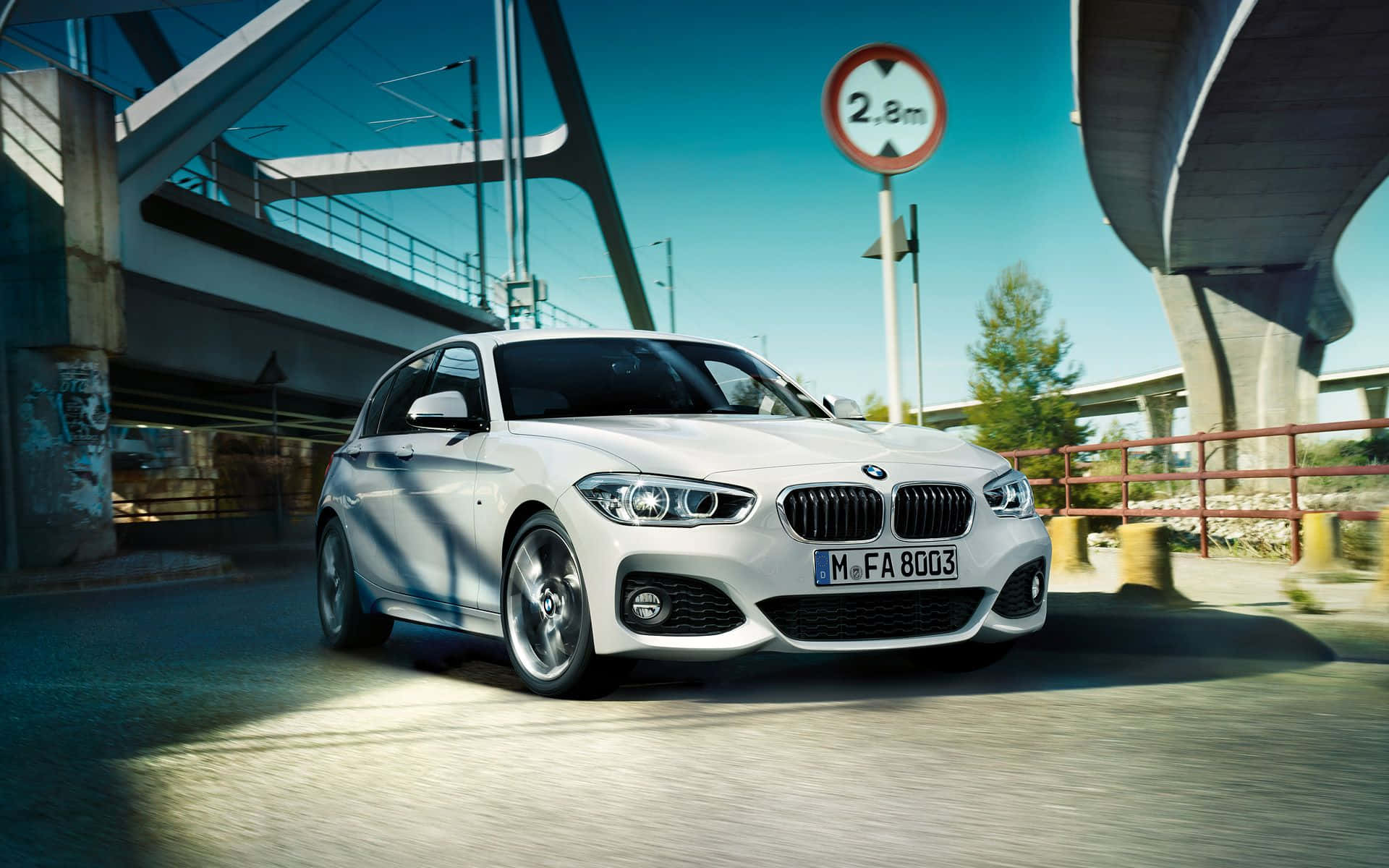 Bmw 1 Series 桌布 壁紙 — 一輛時尚的白色BMW轎車在晴朗的日子裡行駛在現代混凝土天橋下。