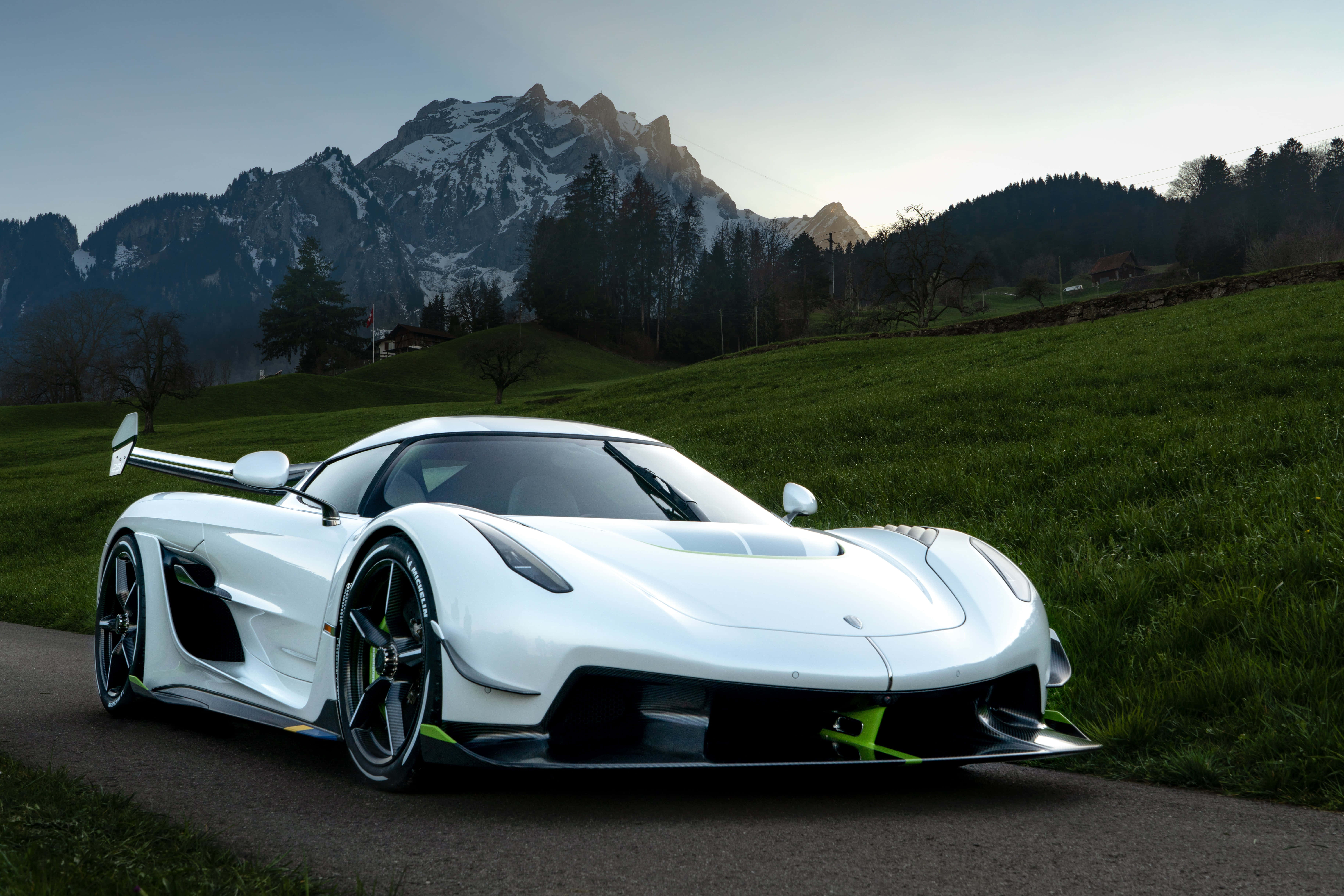 跑車 桌布 壁紙 — 一輛時尚的白色Koenigsegg超跑停在蜿蜒的道路上，背景是黃昏時分積雪的山峰和綠色的山丘。