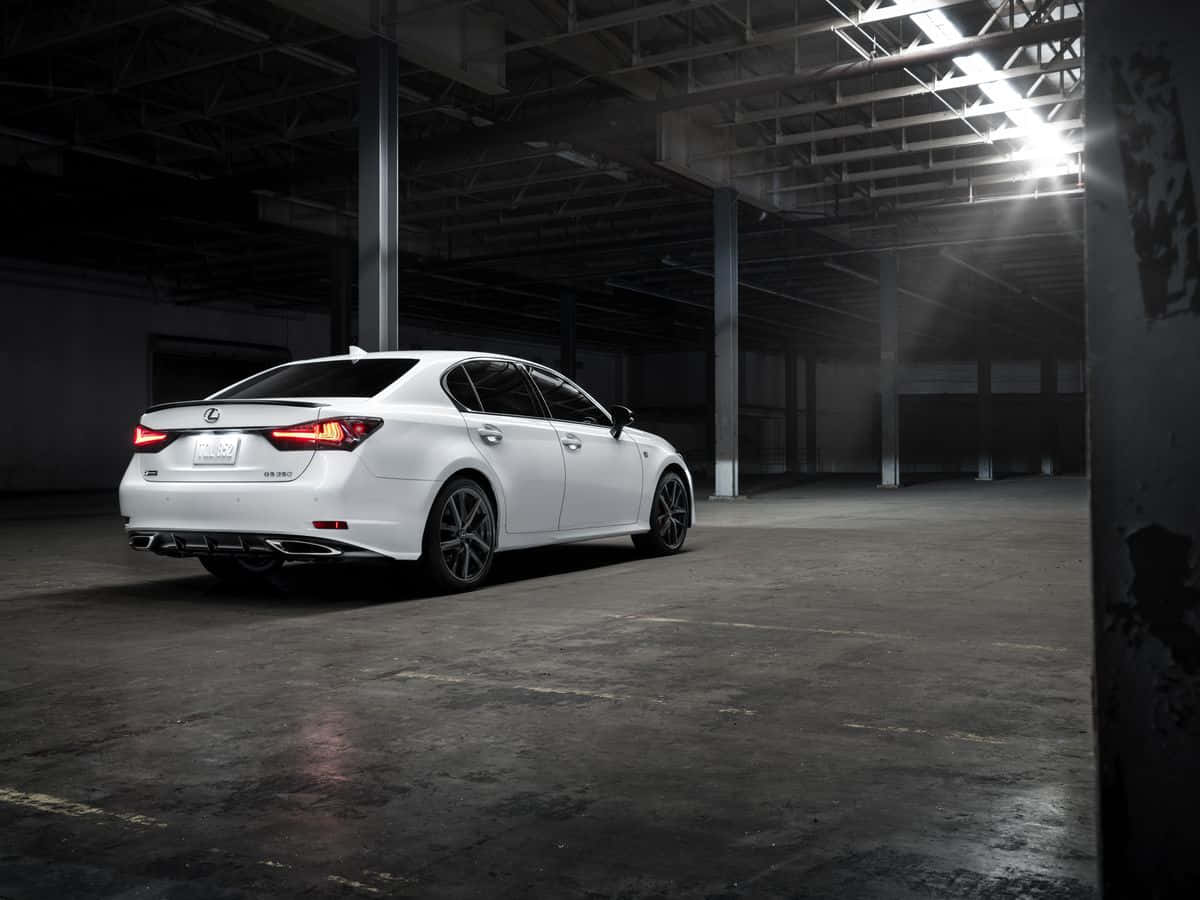Lexus Gs 桌布 壁紙 — 一輛時尚的白色Lexus房車在寬敞昏暗的工業倉庫中，於單一聚光燈下閃閃發光。
