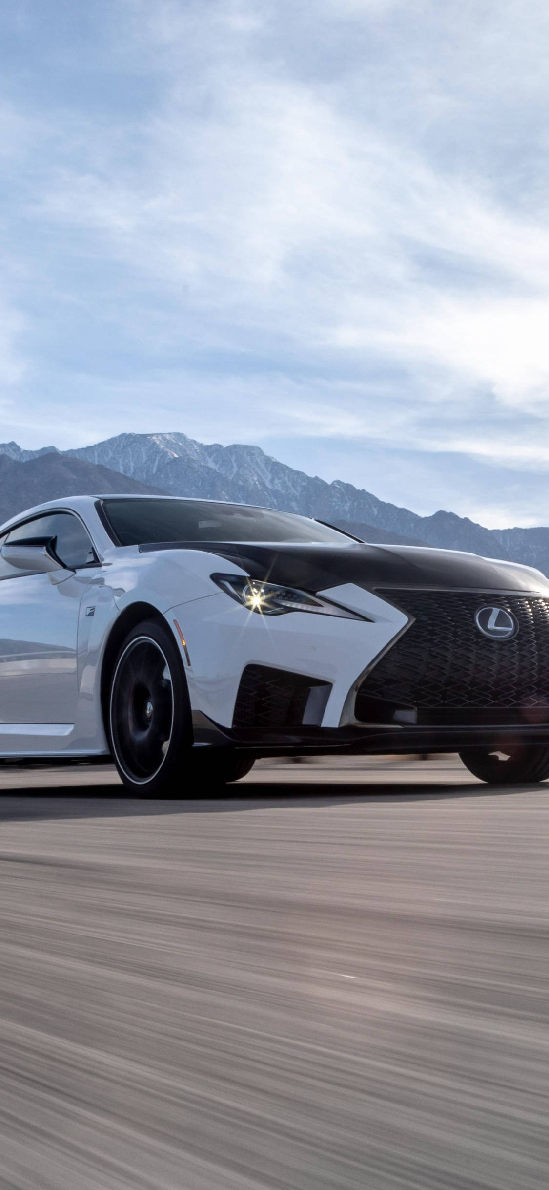 lexus iPhone 桌布 壁紙 — 一輛時尚的白色Lexus跑車在陰天背景下，沿著道路奔馳，背景是積雪的山脈。