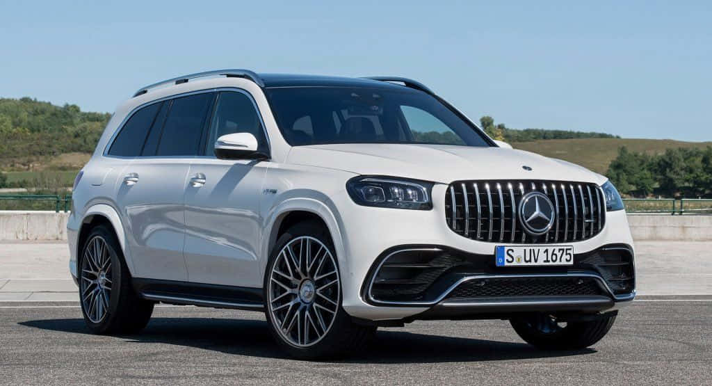 Family Car 桌布 壁紙 — 一輛時尚的白色Mercedes GLS SUV停放在鋪砌路面上，背景是連綿起伏的綠色山丘，天空湛藍清澈。