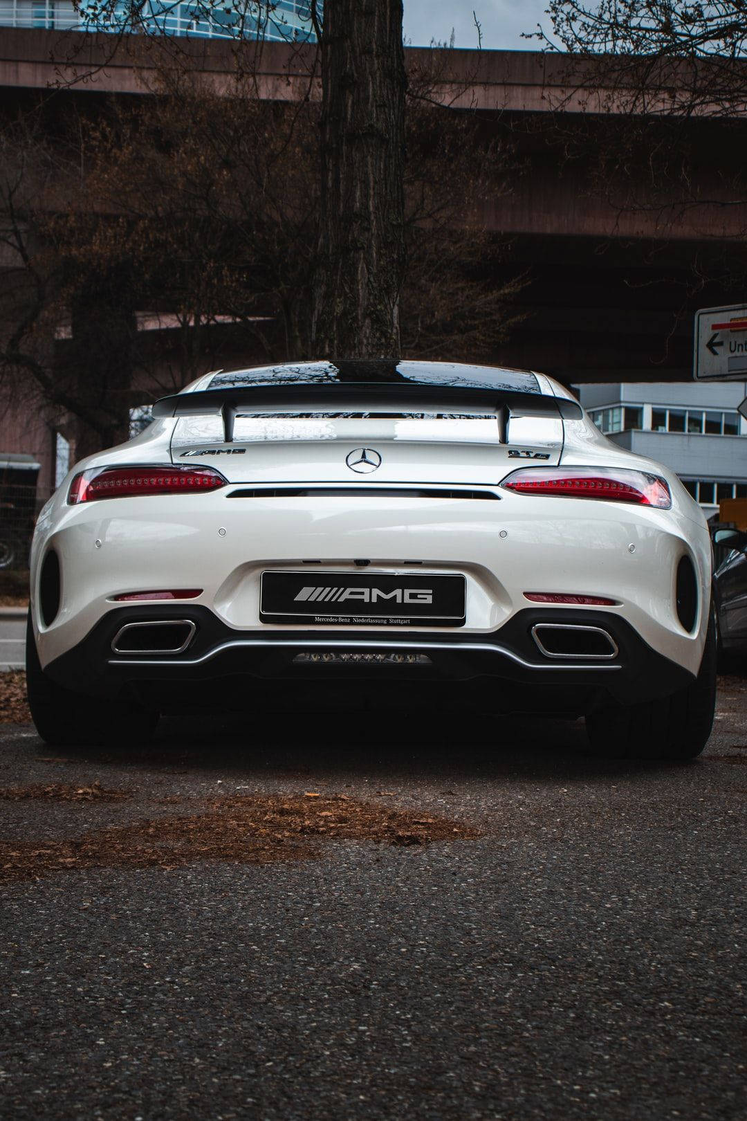 Mercedes 桌布 壁紙 — 一輛時尚的白色Mercedes-AMG GT停在天橋下，瀝青路上散落著秋天的落葉。