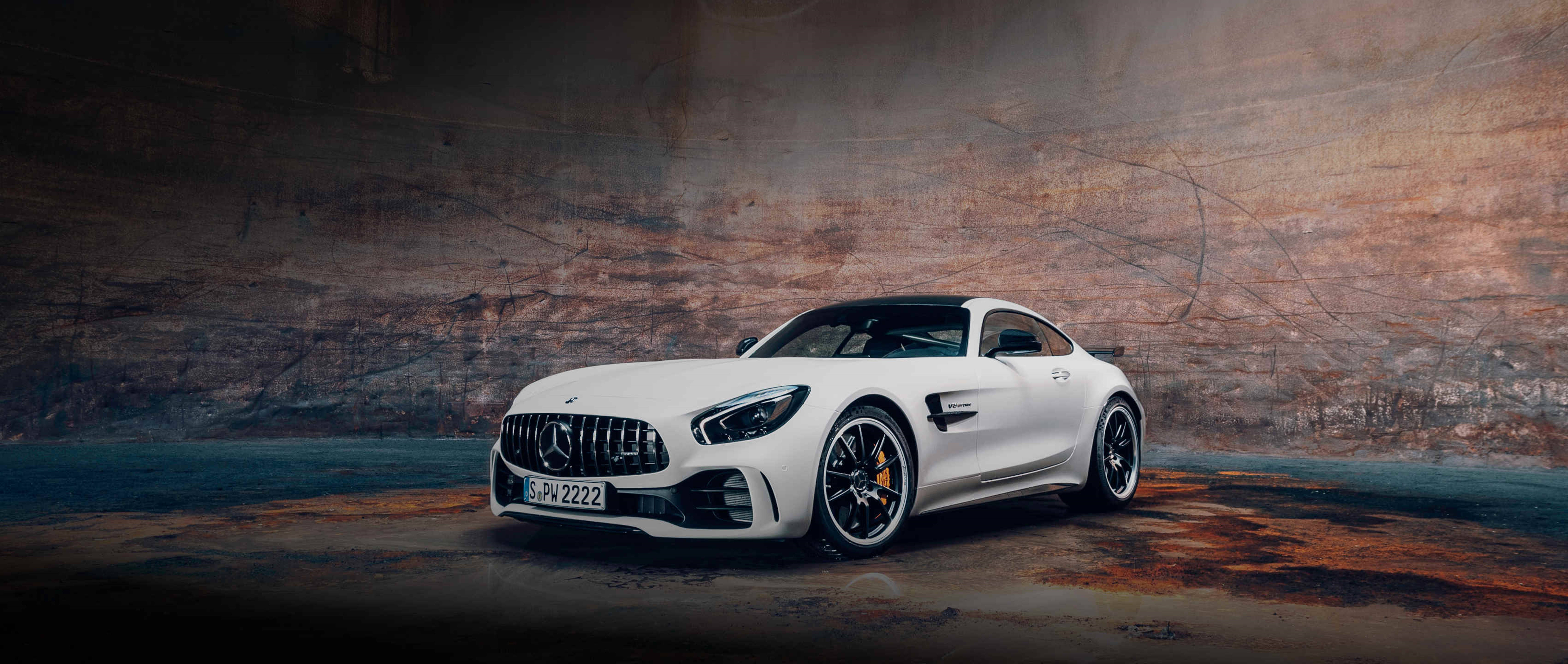 白色Mercedes-AMG GT跑車在黑暗的工業隧道中，牆壁有紋理。 — 4K 奔馳壁紙 壁紙