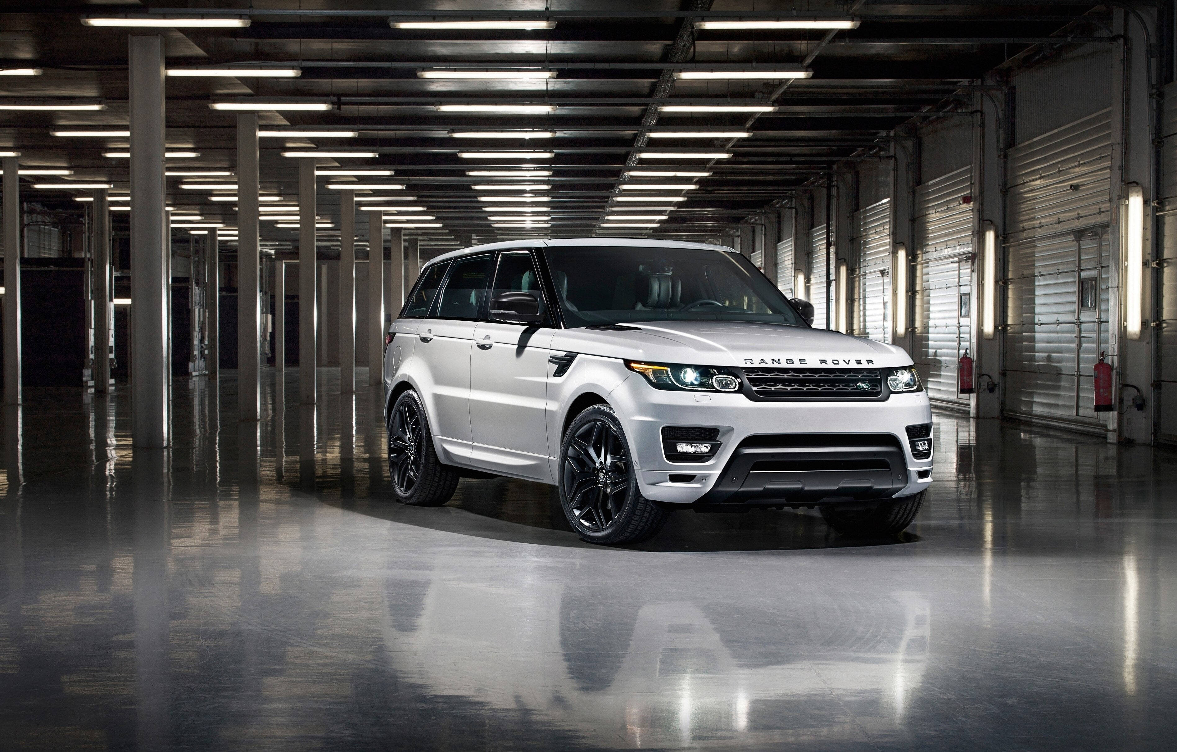 高清 桌布 壁紙 — 一輛時尚的白色Range Rover Sport配黑色輪圈，位於寬敞的工業倉庫中央，地板反射光線，頭頂有燈光。