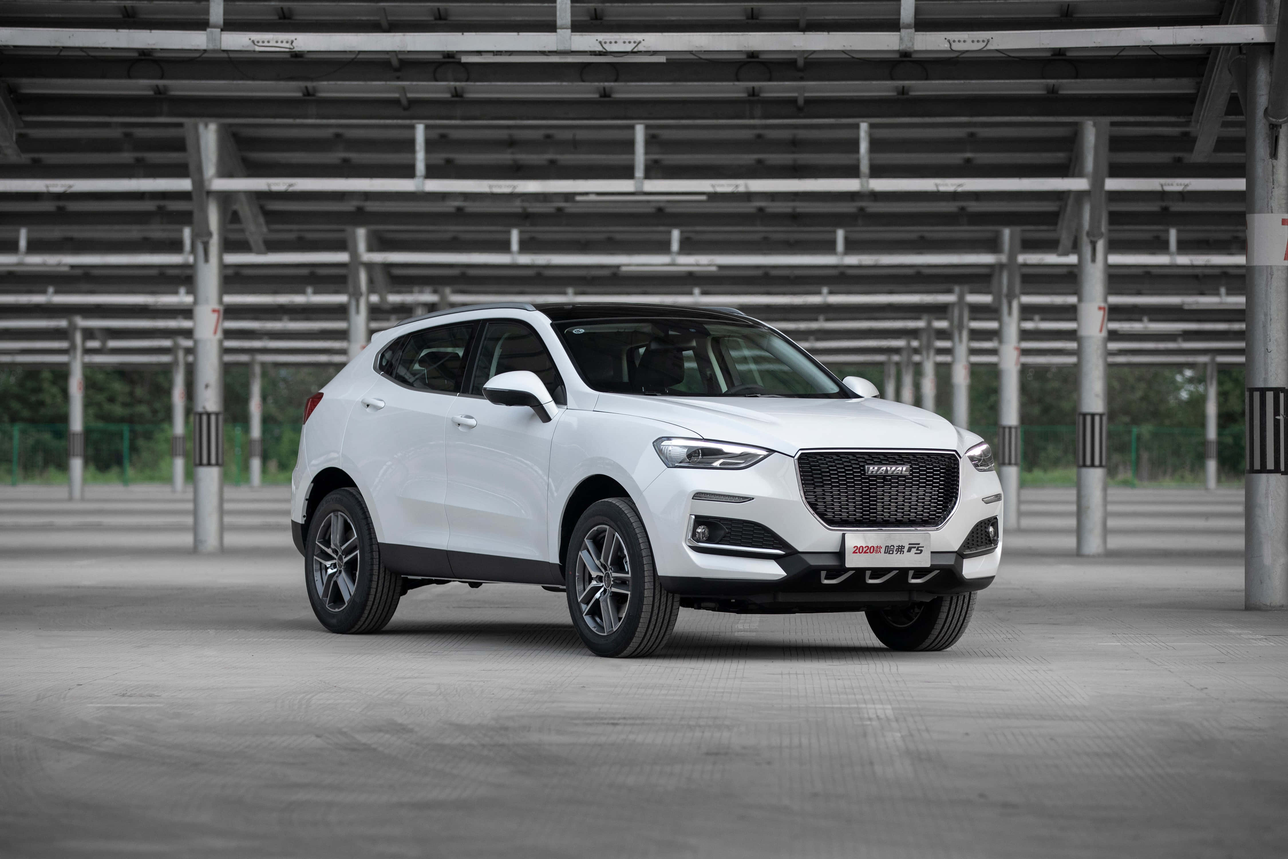 Haval 桌布 壁紙 — 一輛時尚的白色SUV停放在廣闊的工業金屬屋頂下，背景有混凝土柱和綠植。