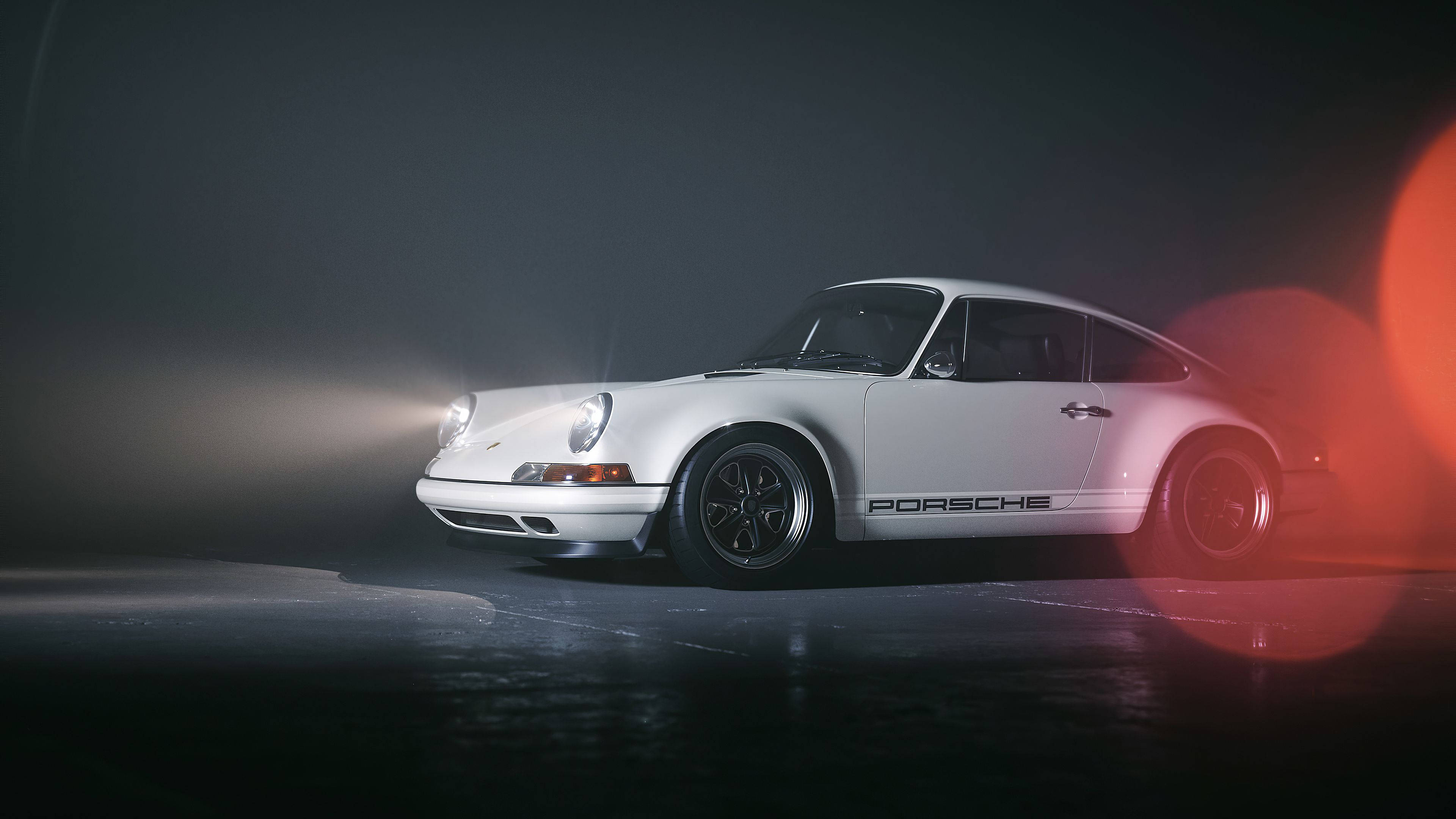 Porsche 911 桌布 壁紙 — 一輛時尚的白色保時捷911在戲劇性的工作室燈光下閃耀，帶有紅色鏡頭光暈，背景是黑暗迷霧。