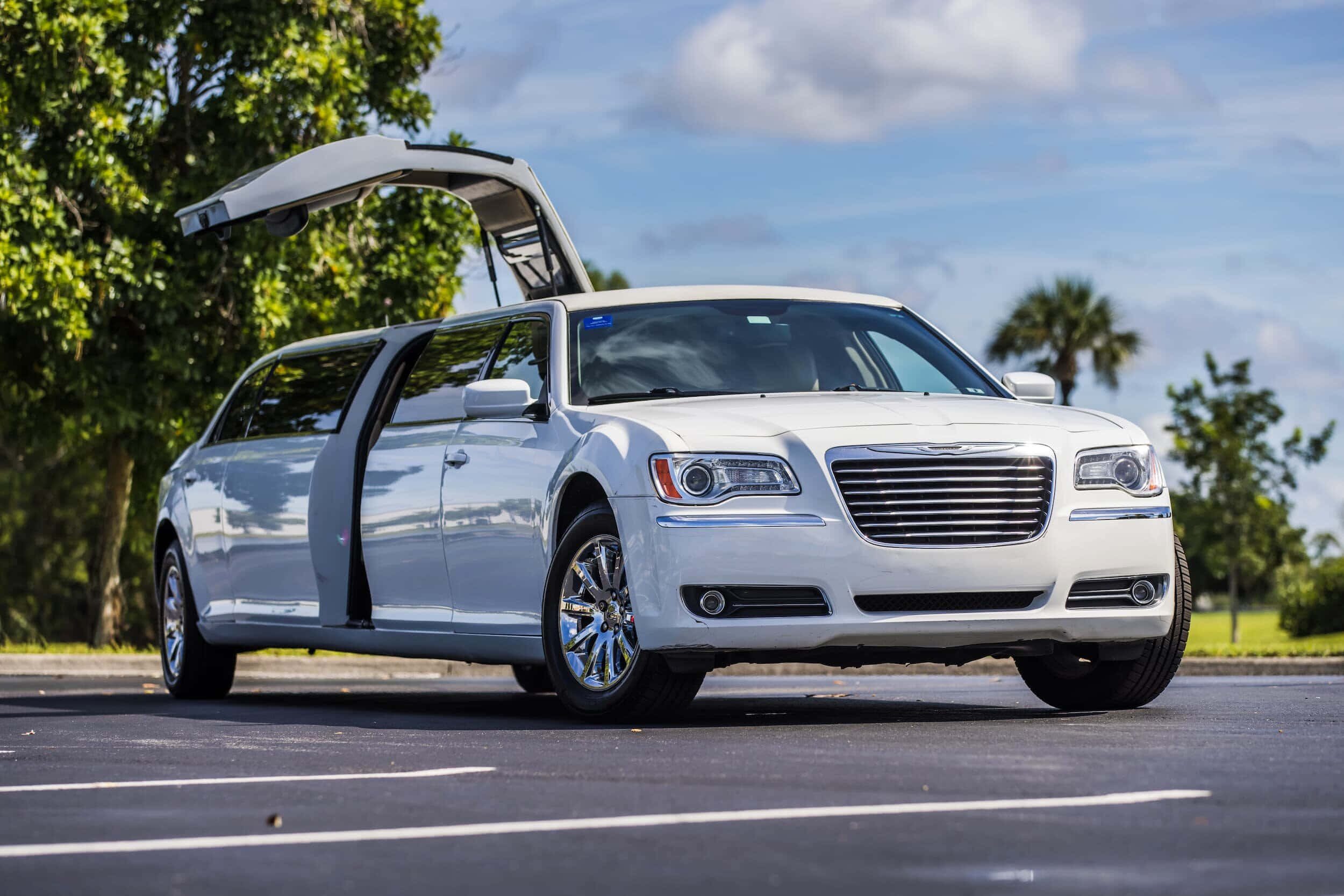 Chrysler 桌布 壁紙 — 一輛時尚的白色加長豪華轎車，後門打開，停放在瀝青停車場，天空局部多雲。