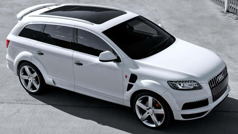 Family Car 桌布 壁紙 — 一輛時尚的白色奧迪Q7 SUV，配備黑色車窗和銀色輪圈，停在明亮的日光下的灰色混凝土表面上。