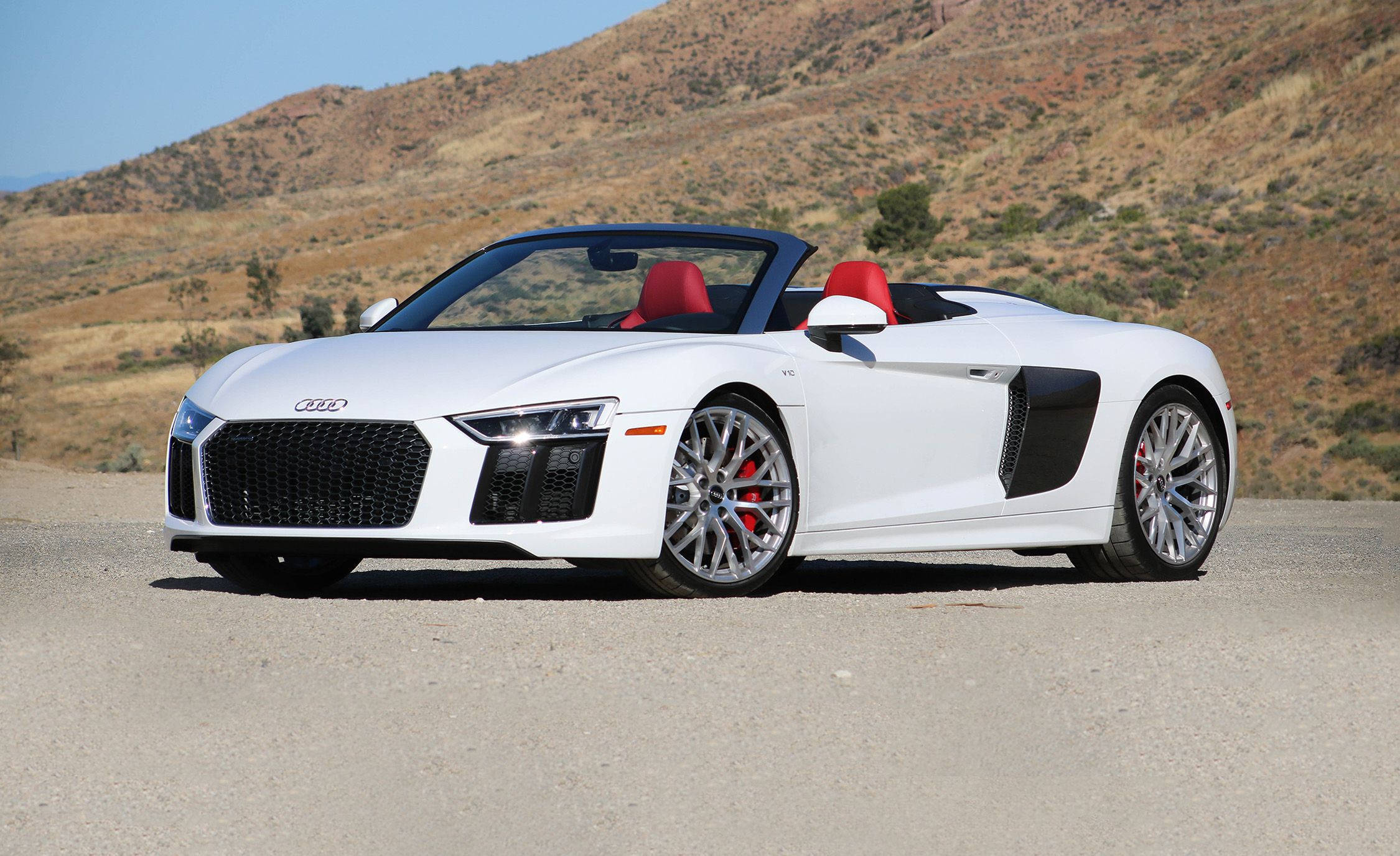 R8 桌布 壁紙 — 一輛時尚的白色奧迪R8 Spyder敞篷車，紅色座椅，停在沙漠公路上，天空湛藍。