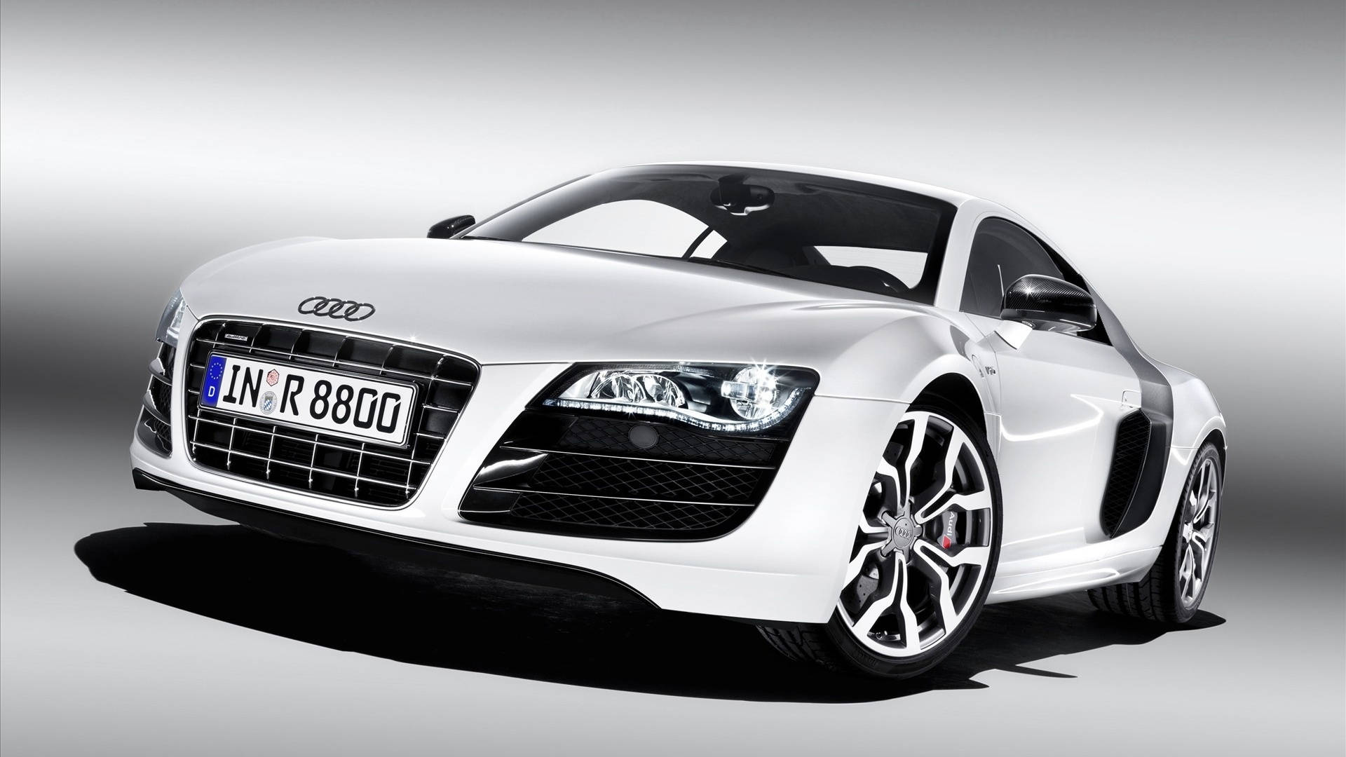 cars 桌布 壁紙 — 一輛時尚的白色奧迪R8跑車，帶有黑色飾邊和發光頭燈，在漸變灰色工作室背景前擺拍。