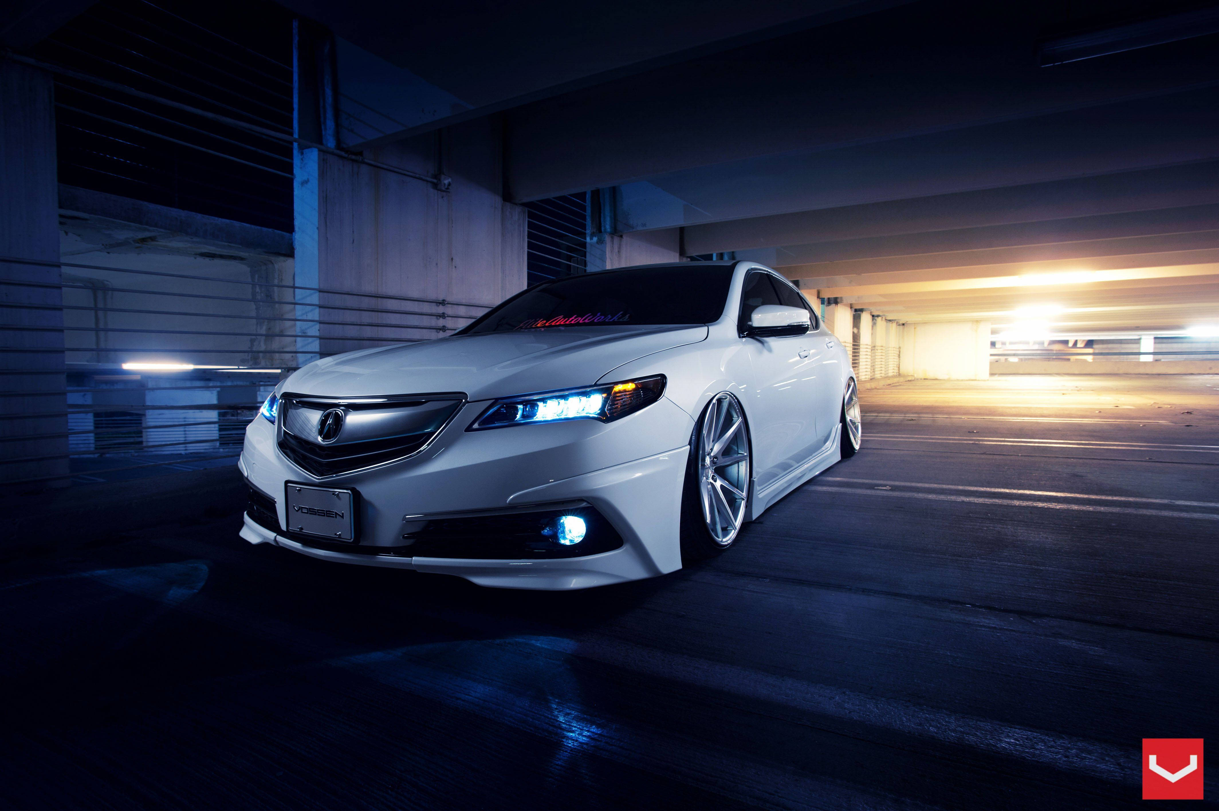 Acura 桌布 壁紙 — 一輛時尚的白色改裝轎車，帶有發光的藍色車頭燈，停在光線昏暗的地下停車場。