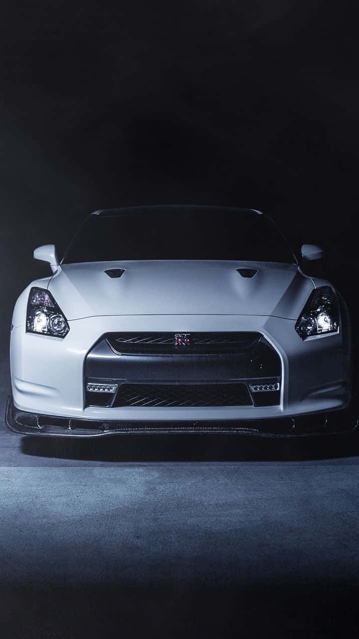 汽車 4K 桌布 壁紙 — 一輛時尚的白色日產GT-R跑車在戲劇性的工作室燈光下，在黑暗背景下閃耀。