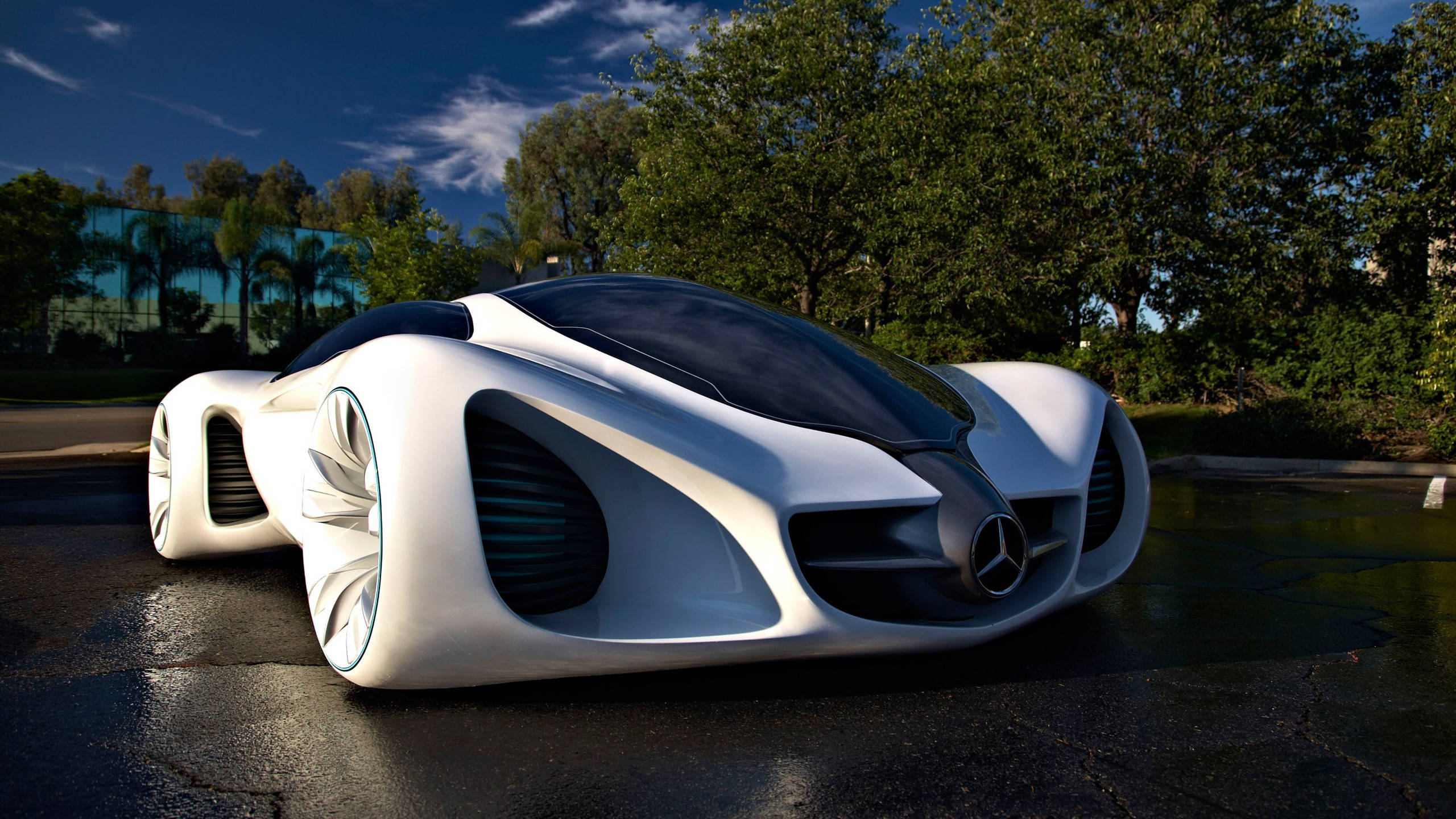 benz 4K 桌布 壁紙 — 一輛時尚的白色未來感賓士概念車，配備發光車輪，停在濕漉漉的路面上，天空清澈湛藍。