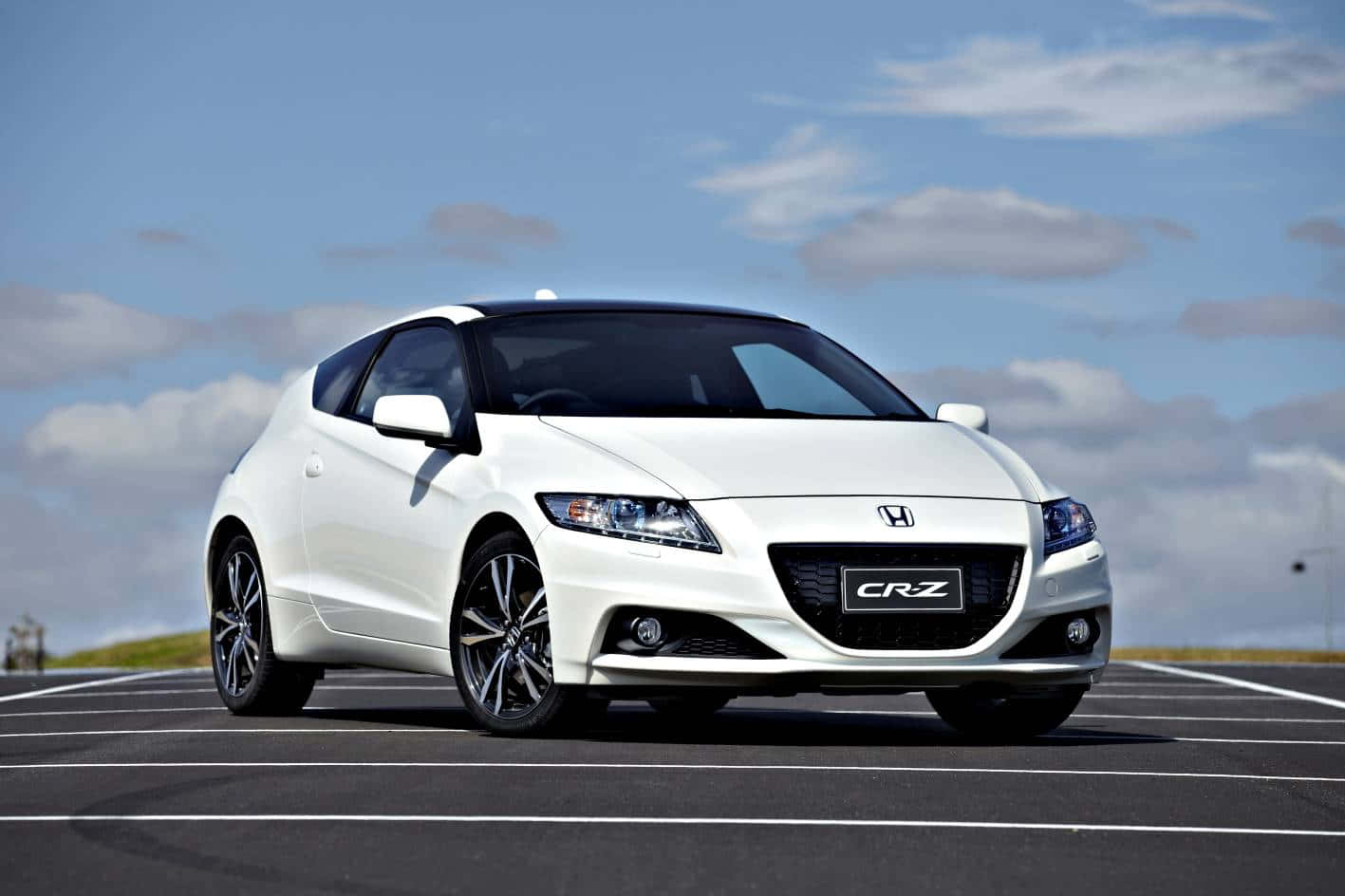 Honda Cr-z 桌布 壁紙 — 一輛時尚的白色本田CRZ跑車停放在瀝青停車場上，天空湛藍，雲朵稀疏。