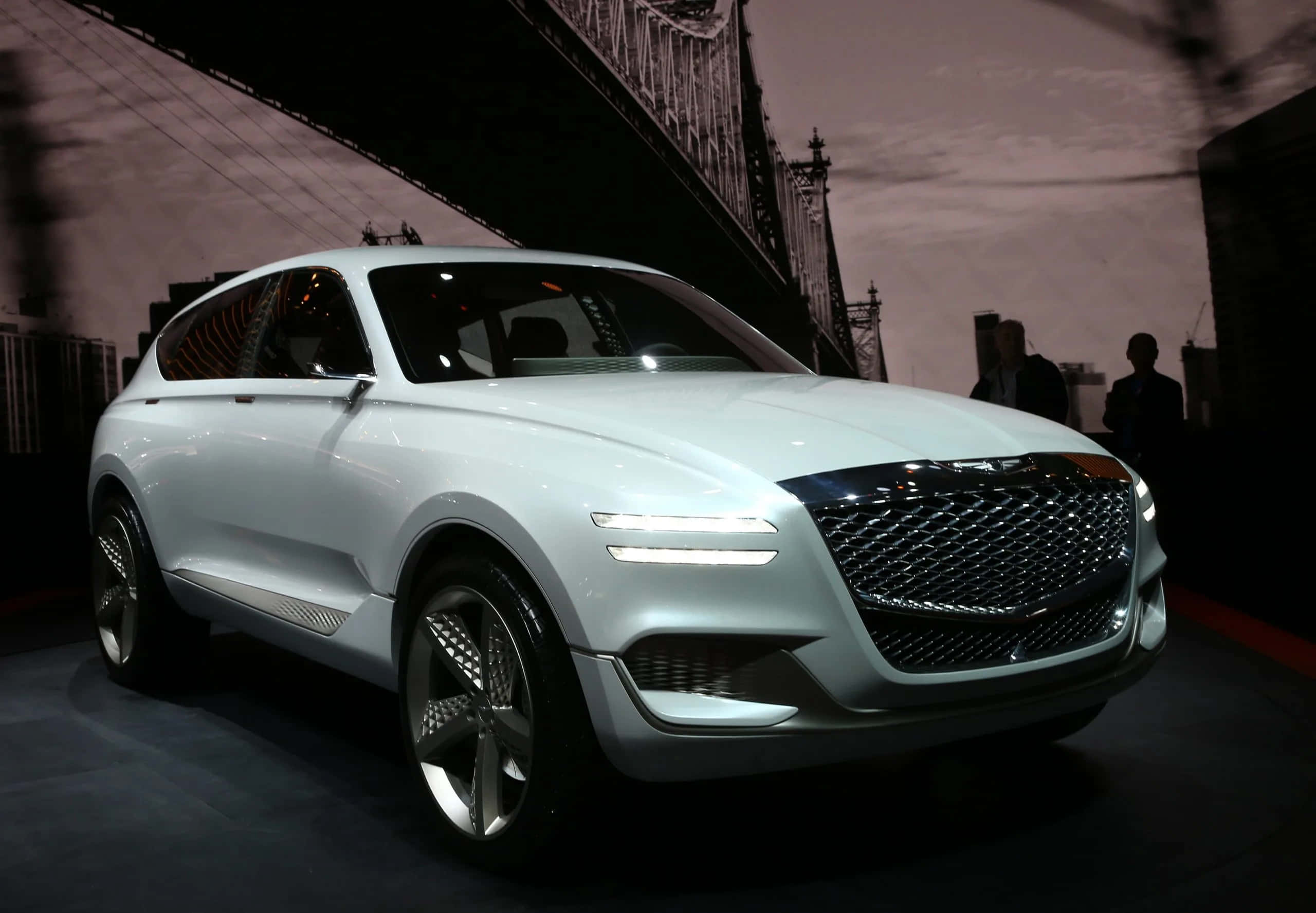Genesis Gv80 桌布 壁紙 — 一輛時尚的白色概念SUV，配備發光頭燈，在戲劇性燈光下以橋樑為背景展示。