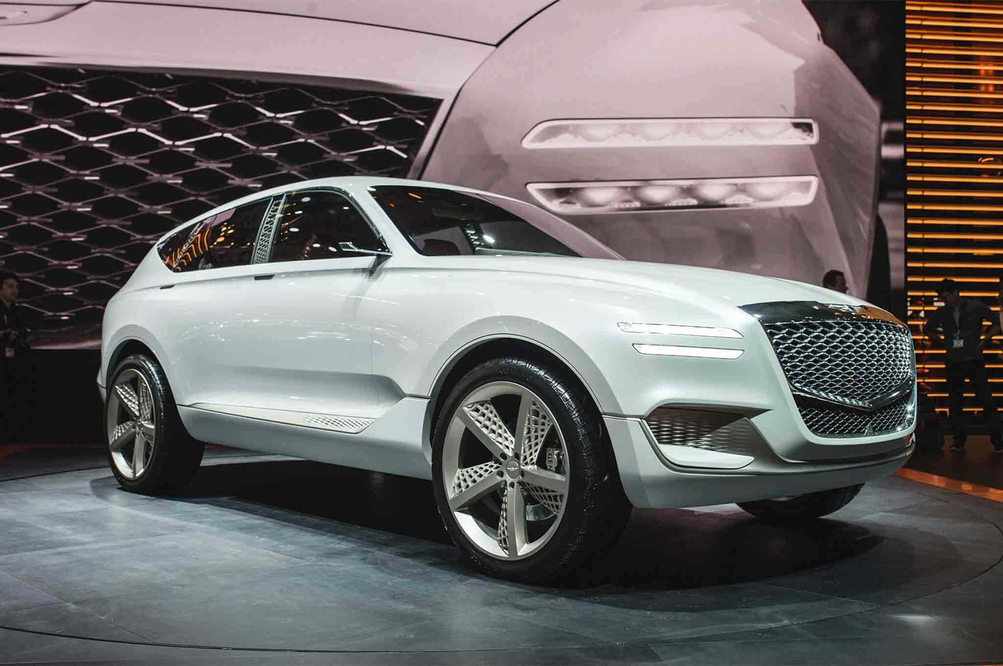 Genesis Gv80 桌布 壁紙 — 一輛時尚的白色概念SUV在車展的圓形舞台上，在明亮的燈光下閃耀，背景是巨大的螢幕。