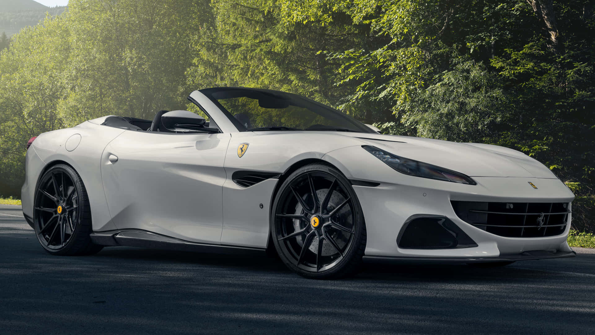 Ferrari Portofino 桌布 壁紙 — 一輛時尚的白色法拉利敞篷車停在森林道路上，背景是茂密的綠樹。