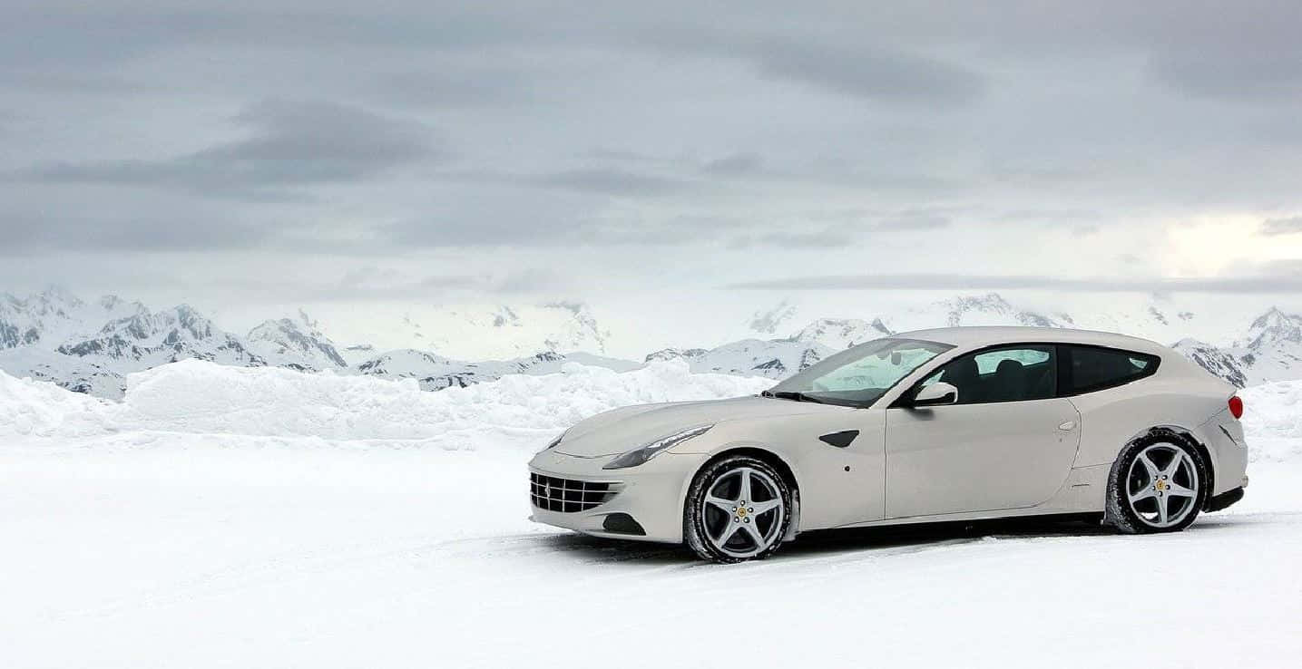 Ferrari Ff 桌布 壁紙 — 一輛時尚的白色法拉利跑車停歇在雪原上，背景是白雪覆蓋的山脈，天空多雲。