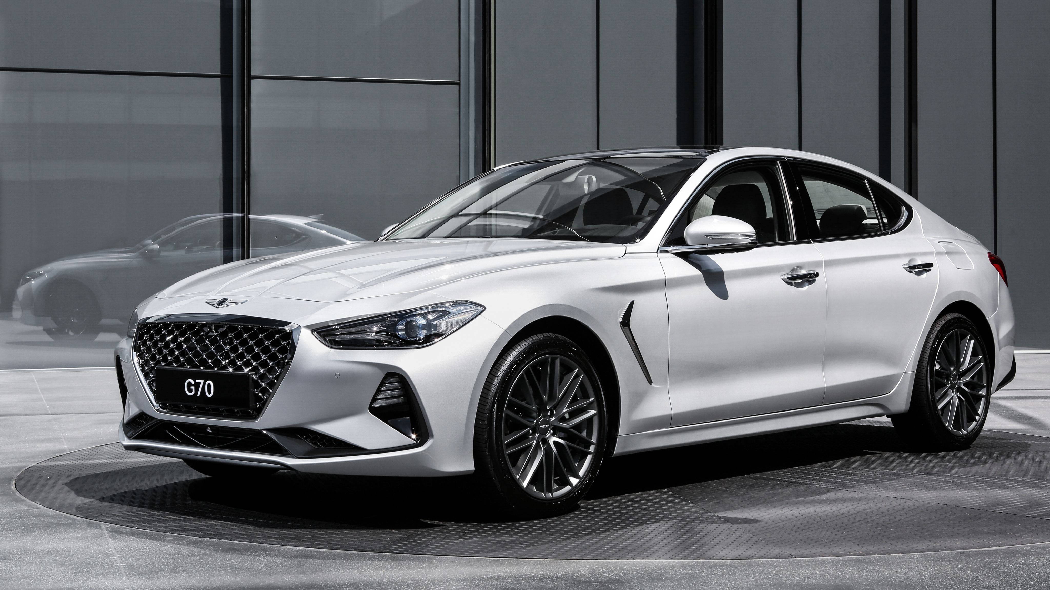 Genesis 桌布 壁紙 — 一輛時尚的白色現代 G70 轎車在現代玻璃牆展廳的攝影棚燈光下閃閃發光。