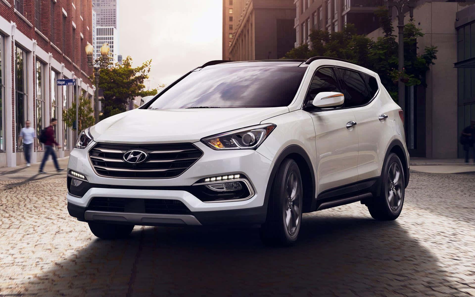Hyundai Santa Fe 桌布 壁紙 — 一輛時尚的白色現代SUV停泊在鵝卵石城市街道上，背景有行人和磚砌建築。