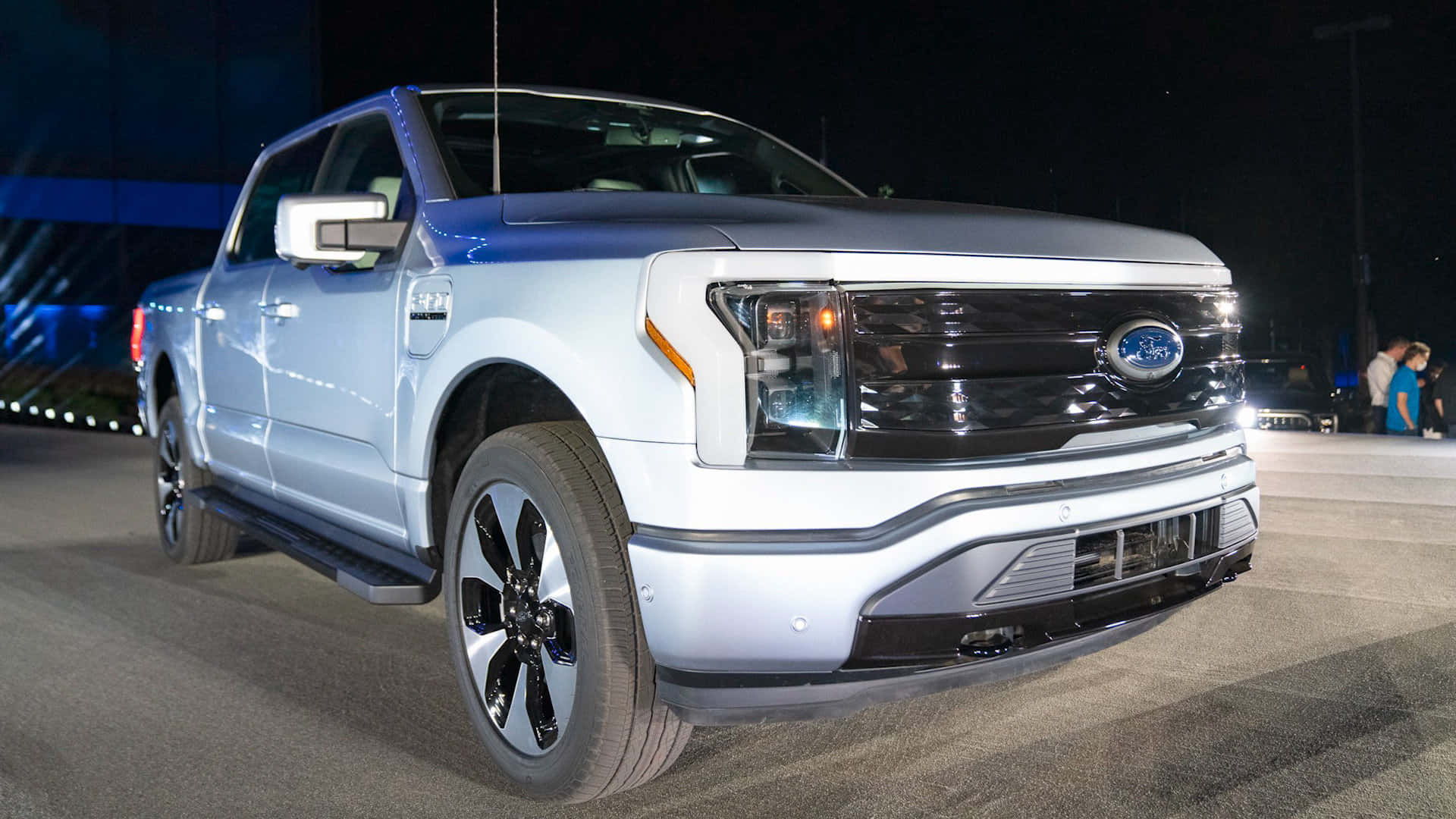 Ford Truck 桌布 壁紙 — 一輛時尚的白色福特F-150 Lightning電動皮卡在夜間車展的明亮舞台燈光下閃閃發光。