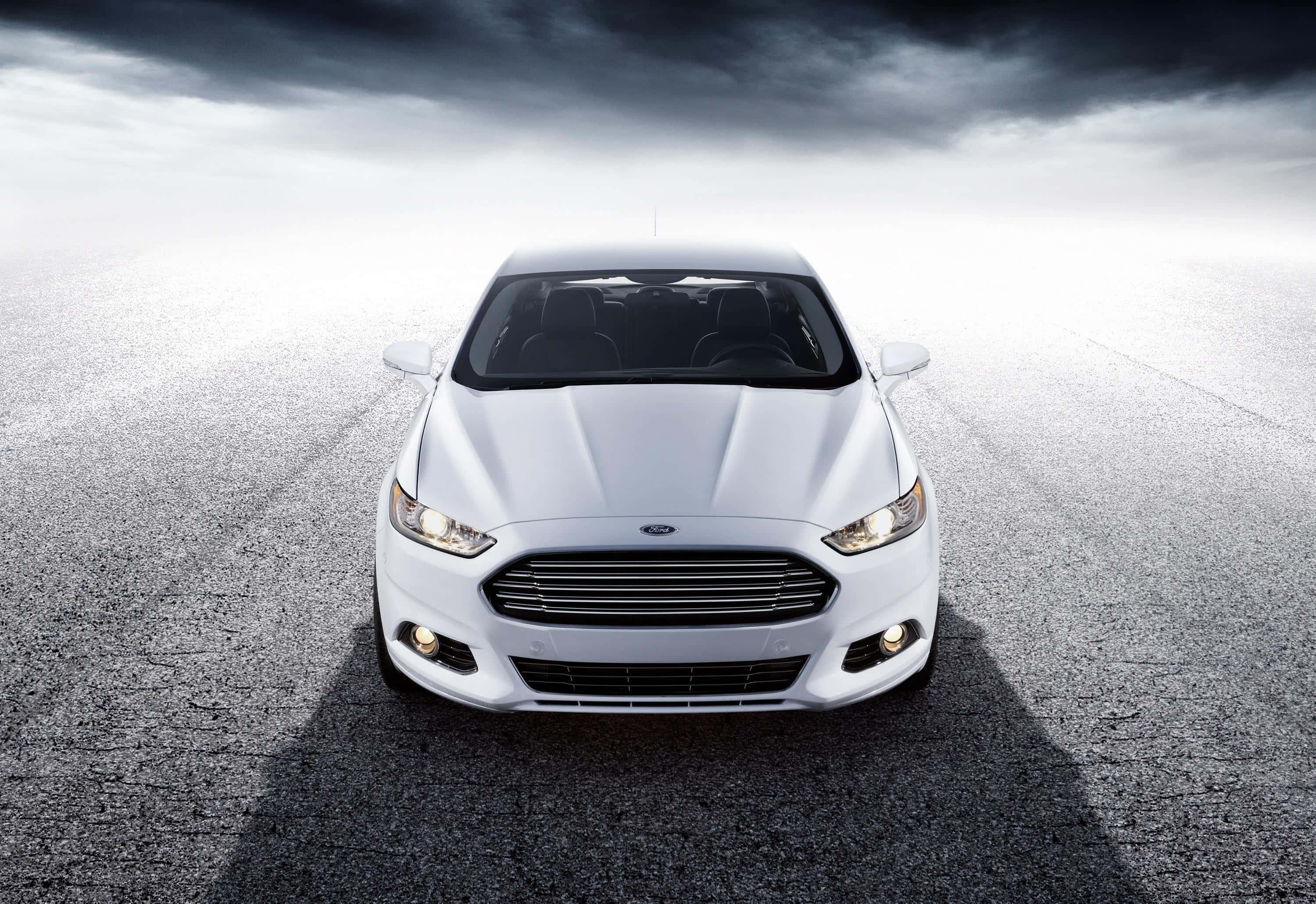 Ford Fusion 桌布 壁紙 — 一輛時尚的白色福特轎車在裂開的瀝青路上向前行駛，天空烏雲密佈，氣氛戲劇化。