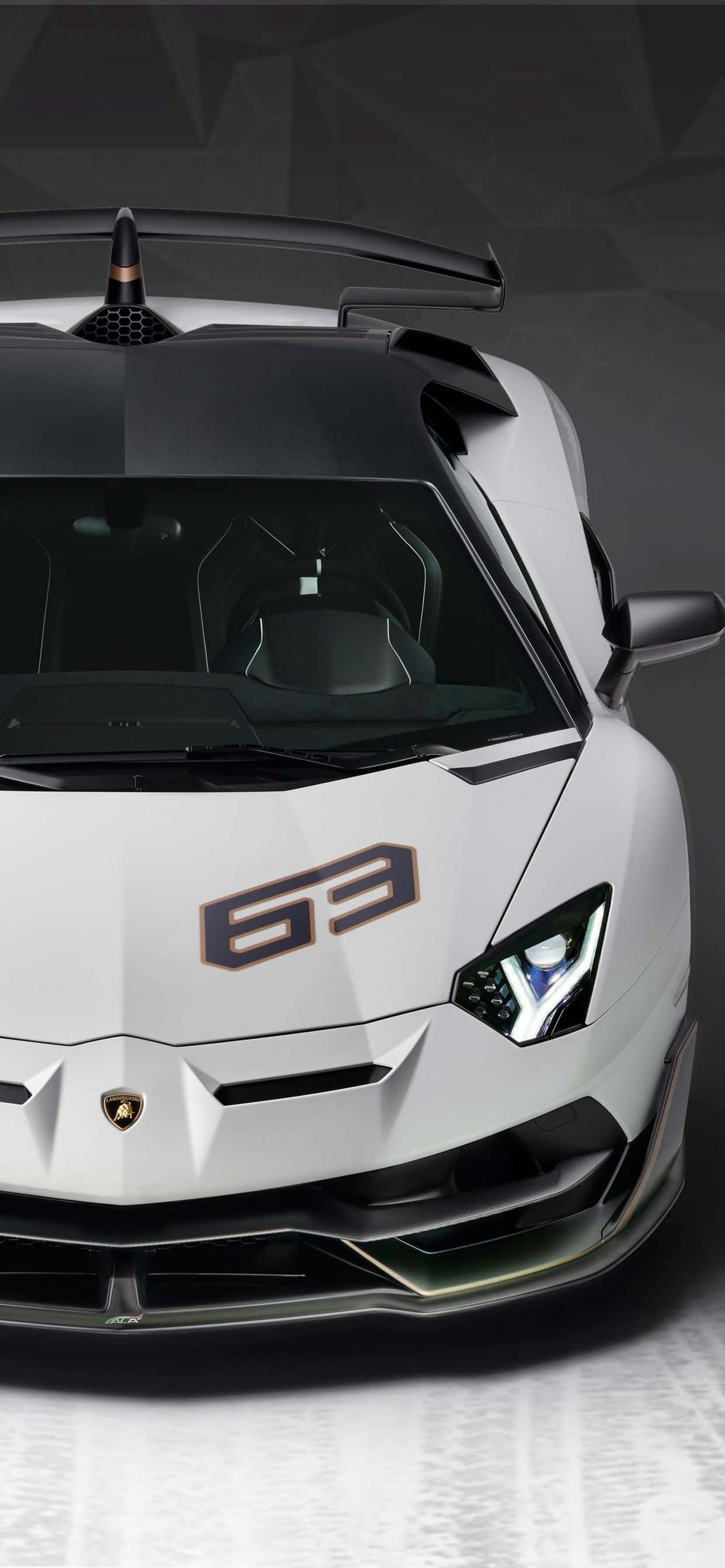 Lamborghini Phone 桌布 壁紙 — 一輛時尚的白色藍寶堅尼 Aventador SVJ 63，帶有黑色飾邊和銳利的角形頭燈，從高角度正面視角觀看，背景為深色幾何圖案。