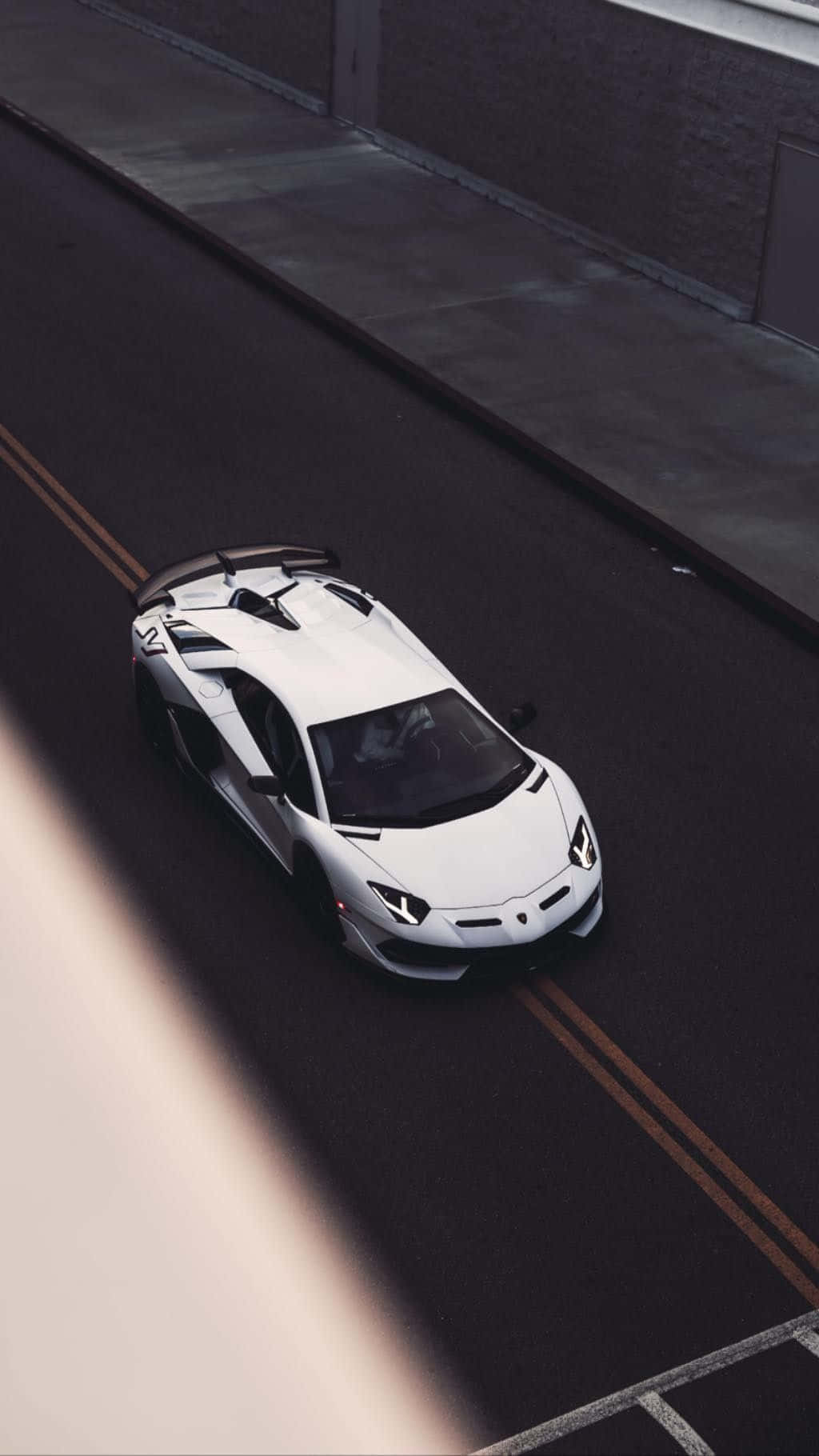 Minimalist Car 桌布 壁紙 — 一輛時尚的白色藍寶堅尼 Aventador SVJ 從高角度在陽光明媚的城市街道上奔馳。