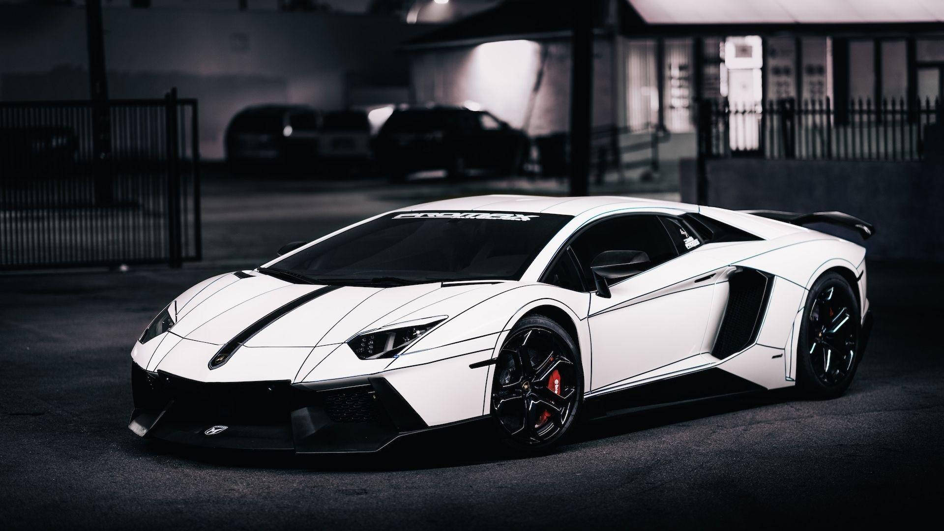 蘭博基尼 桌布 壁紙 — 一輛時尚的白色藍寶堅尼Aventador，帶有黑色飾邊和紅色制動卡鉗，停在光線昏暗的城市車庫中。