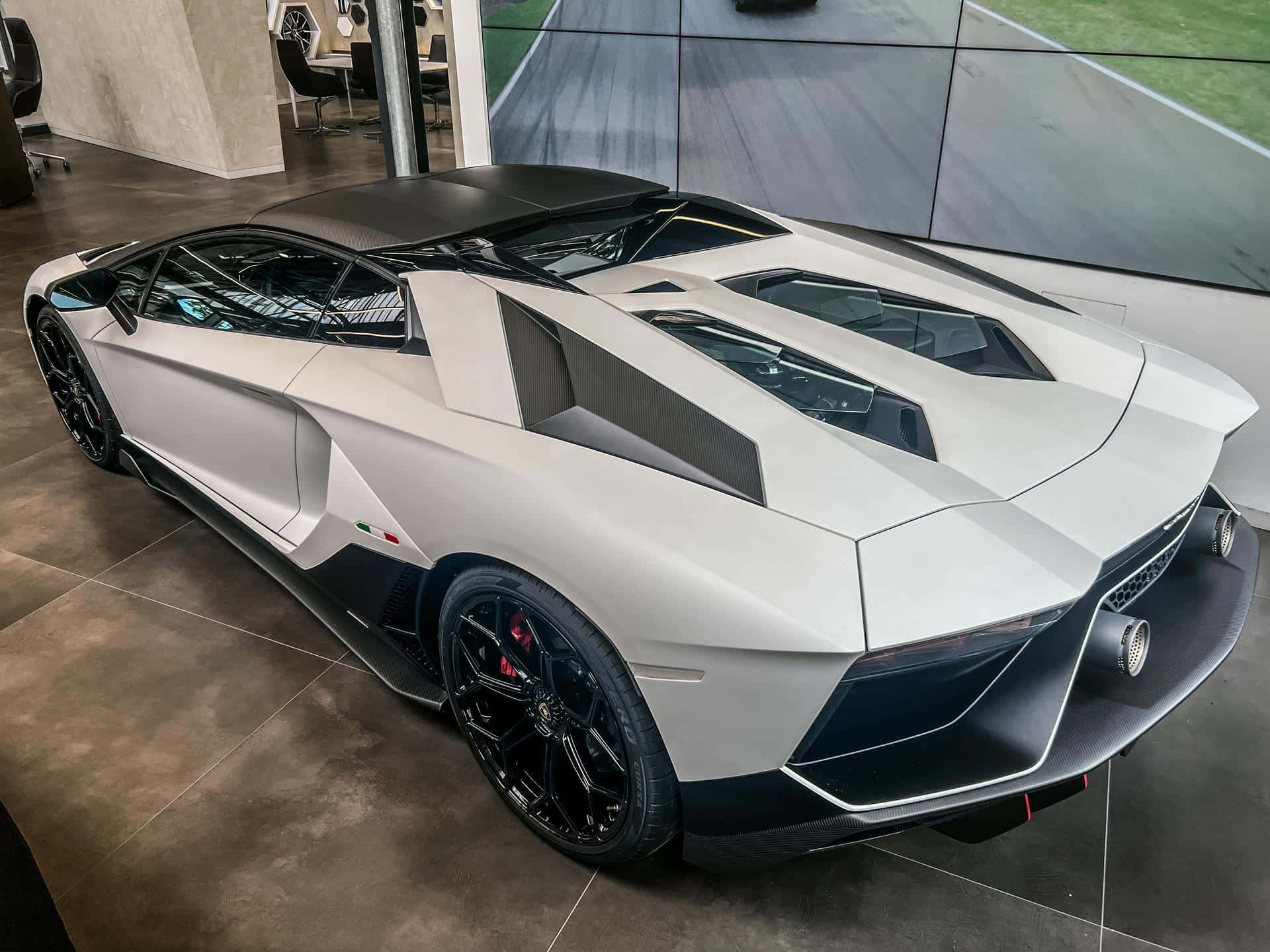 Lamborghini Aventador 桌布 壁紙 — 一輛時尚的白色藍寶堅尼Aventador，帶有黑色飾邊和紅色制動卡鉗，在現代化展示廳中展示，配有大玻璃窗。