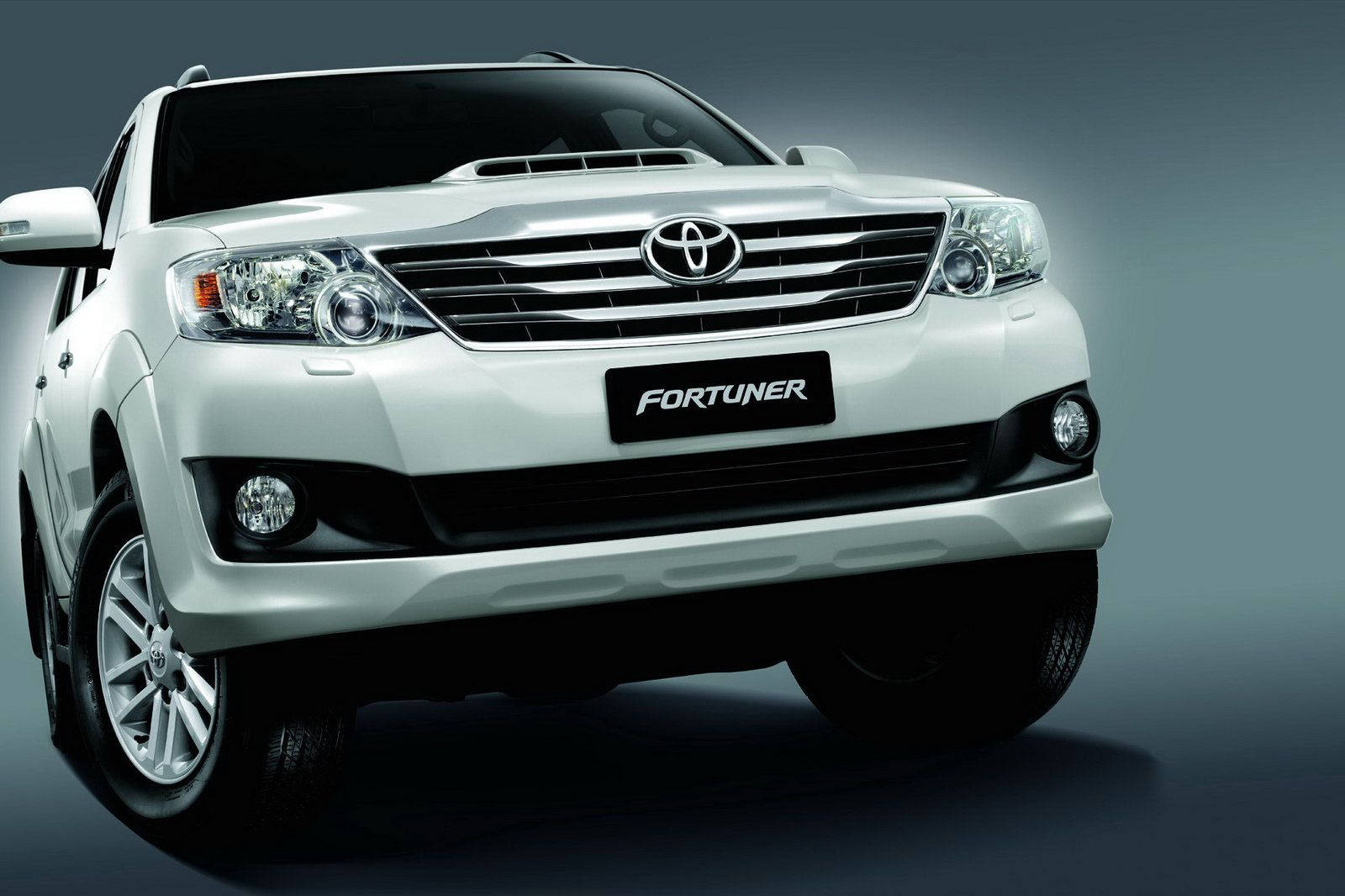 Toyota 桌布 壁紙 — 一輛時尚的白色豐田 Fortuner SUV 在攝影棚內展示，戲劇性的燈光凸顯其現代化的水箱護罩和頭燈。